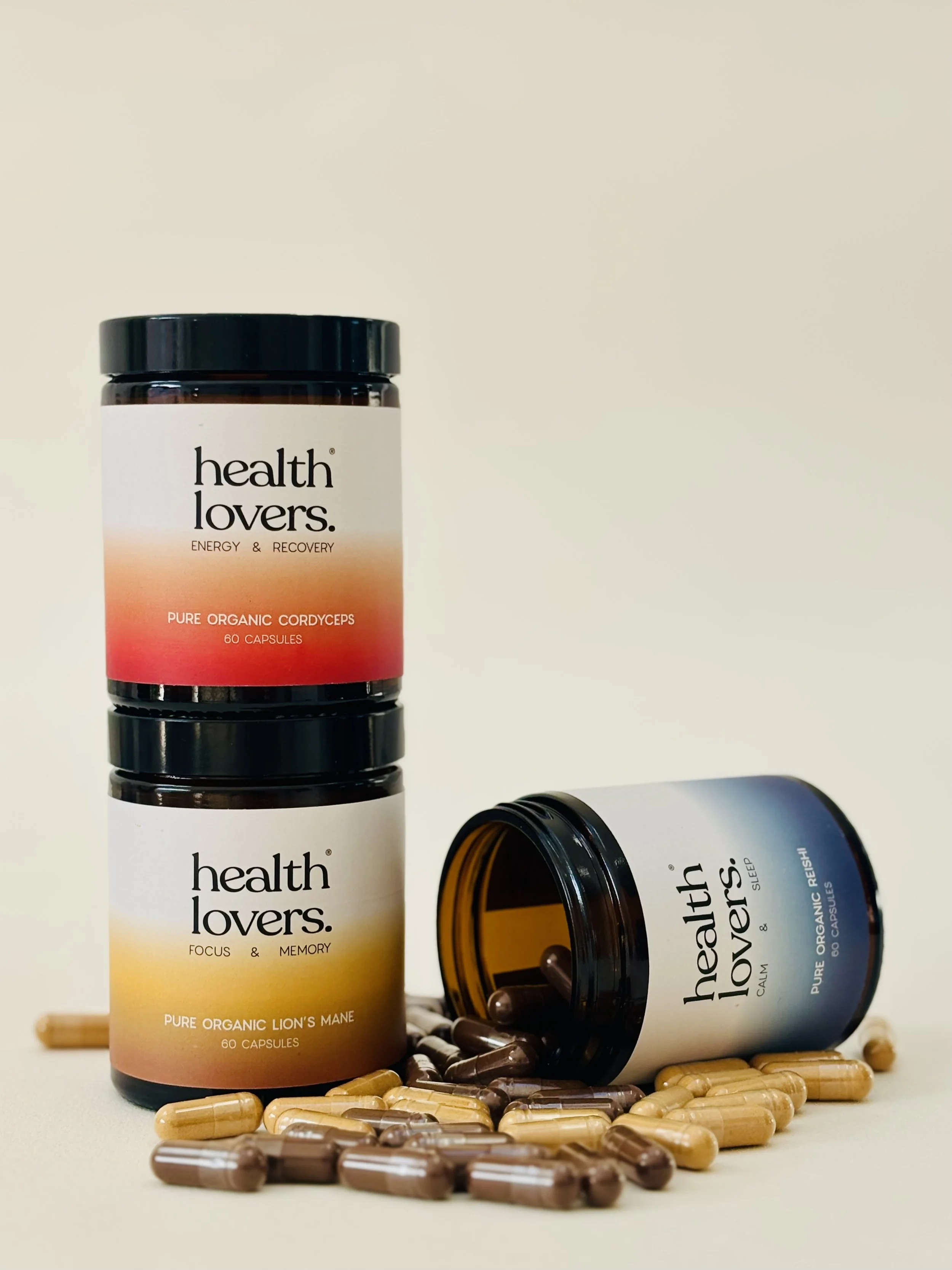 Three bottles of health supplements labeled 'health lovers.' with capsules spilled around them. Two bottles are stacked vertically, and one bottle is laying on its side with capsules spilled out.