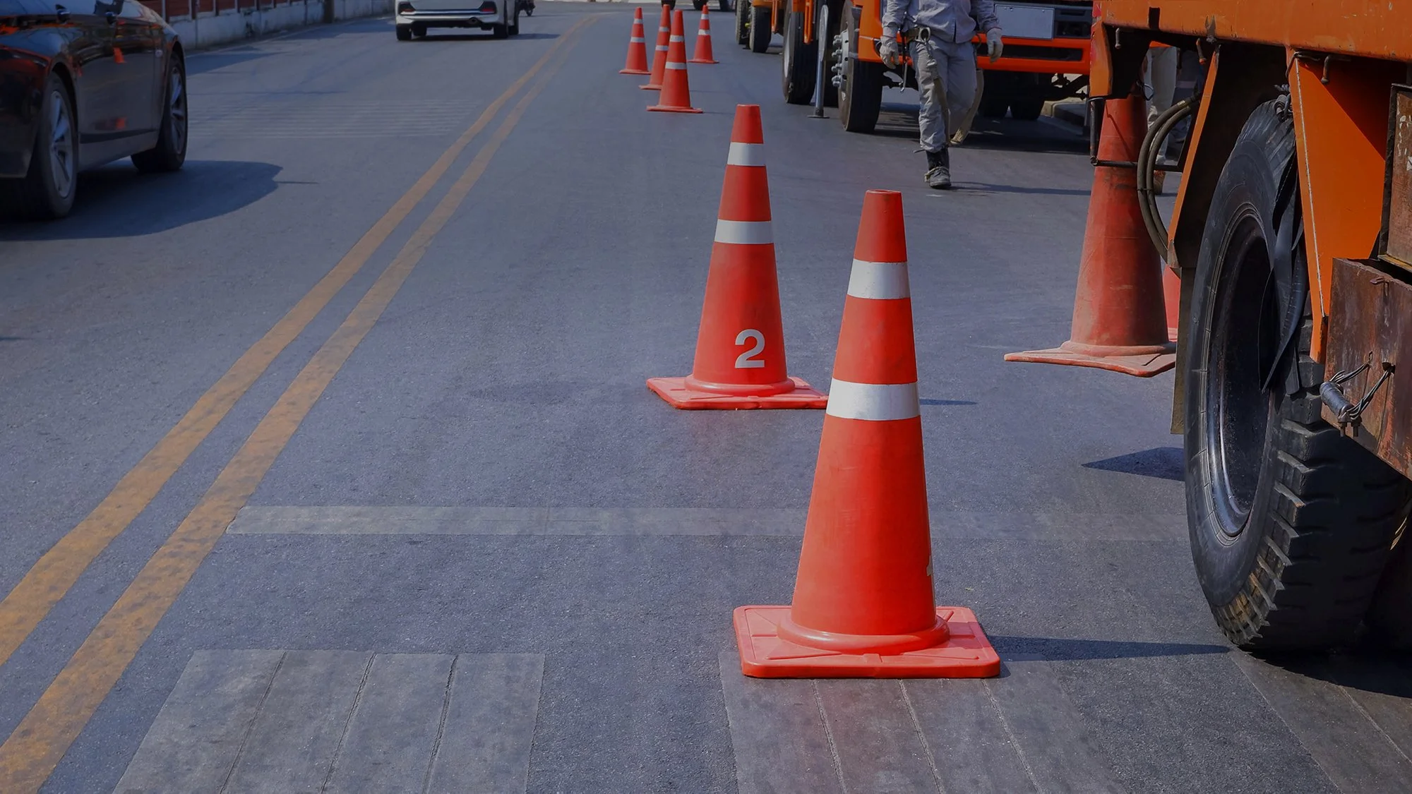 row-traffic-cones-with-low-section-crane-trucks-parking-asphalt-road.jpg