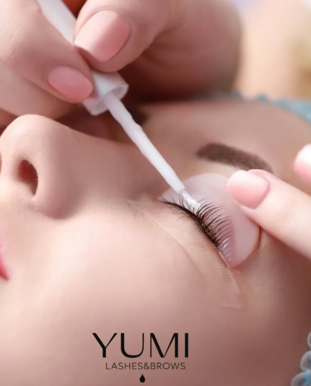 Close-up of a person getting a YUMI Korean Lash Lift applied by a beauty technician using a cotton swab; focus on eye, lashes, and technician's hand.