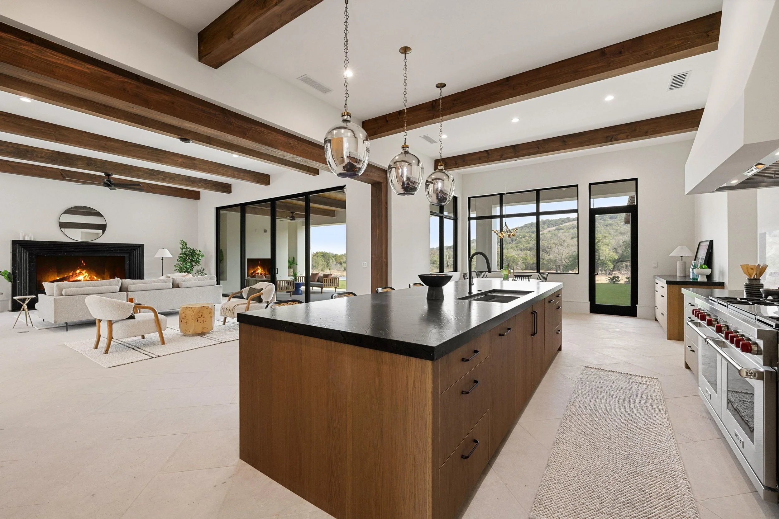 Contemporary kitchen design with island, wood ceiling beams, and expansive windows