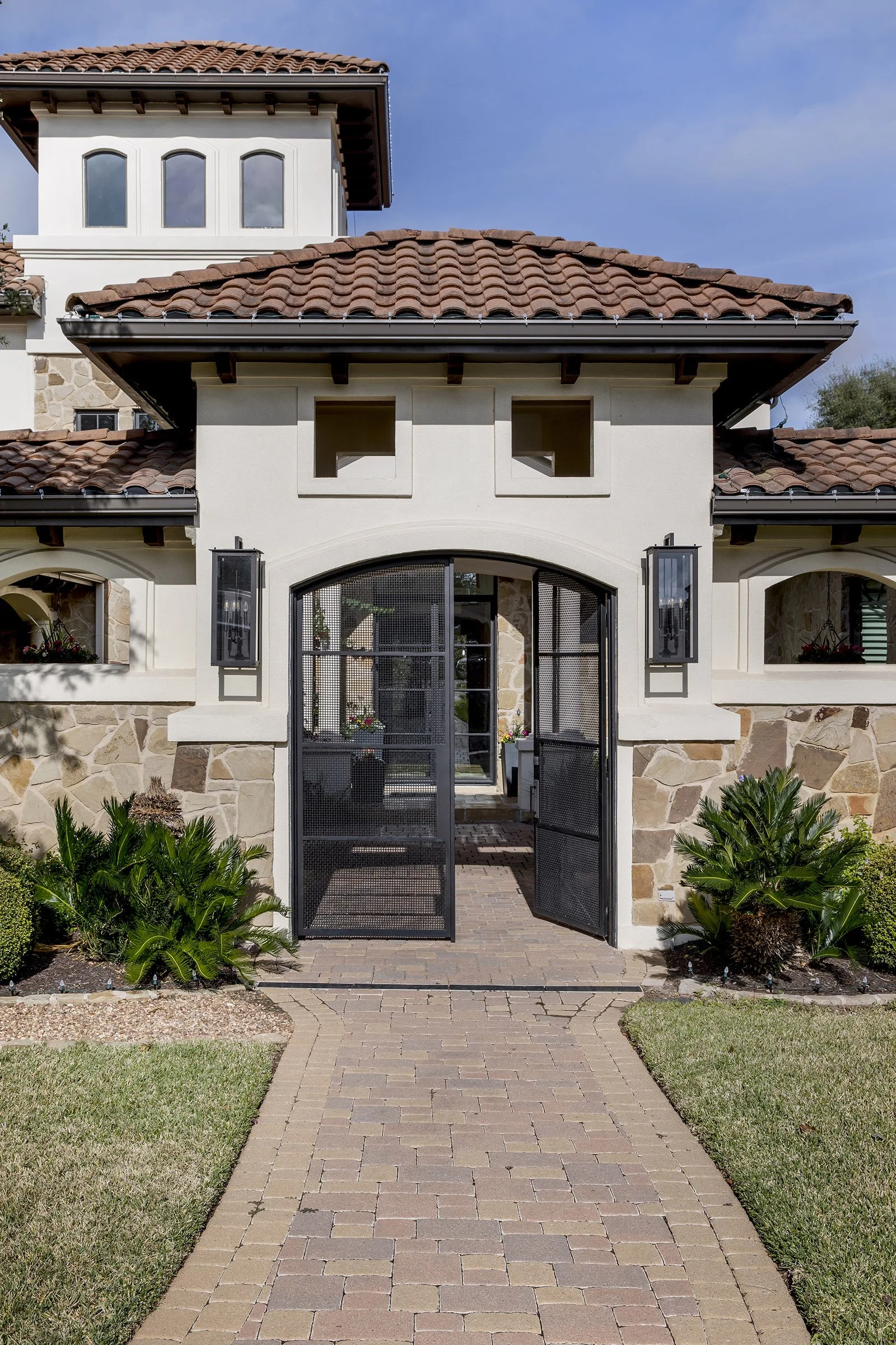 Mediterranean home exterior with arched entry, tile roof, and iron gate