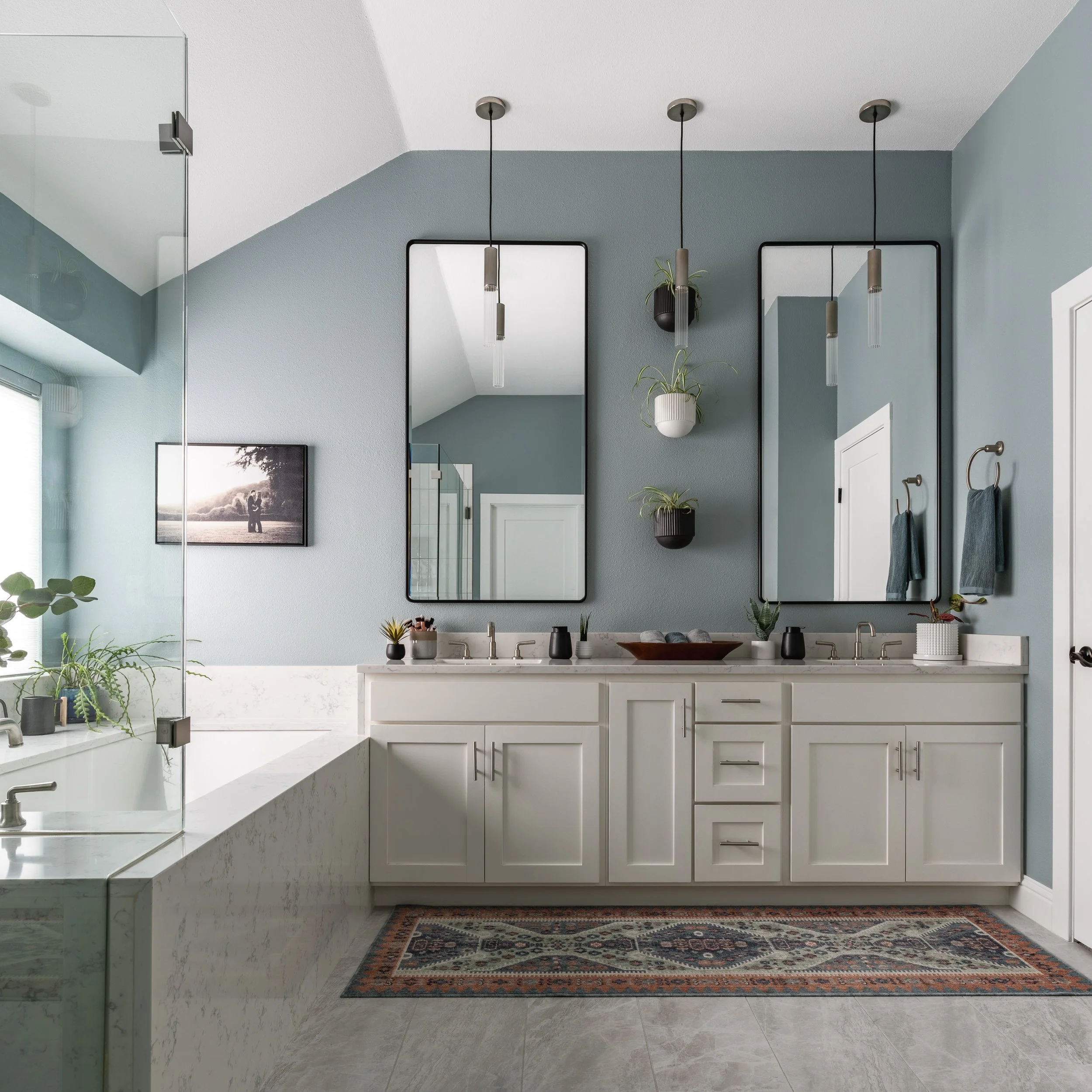 Modern bathroom design with double vanity, blue walls, and glass shower enclosure