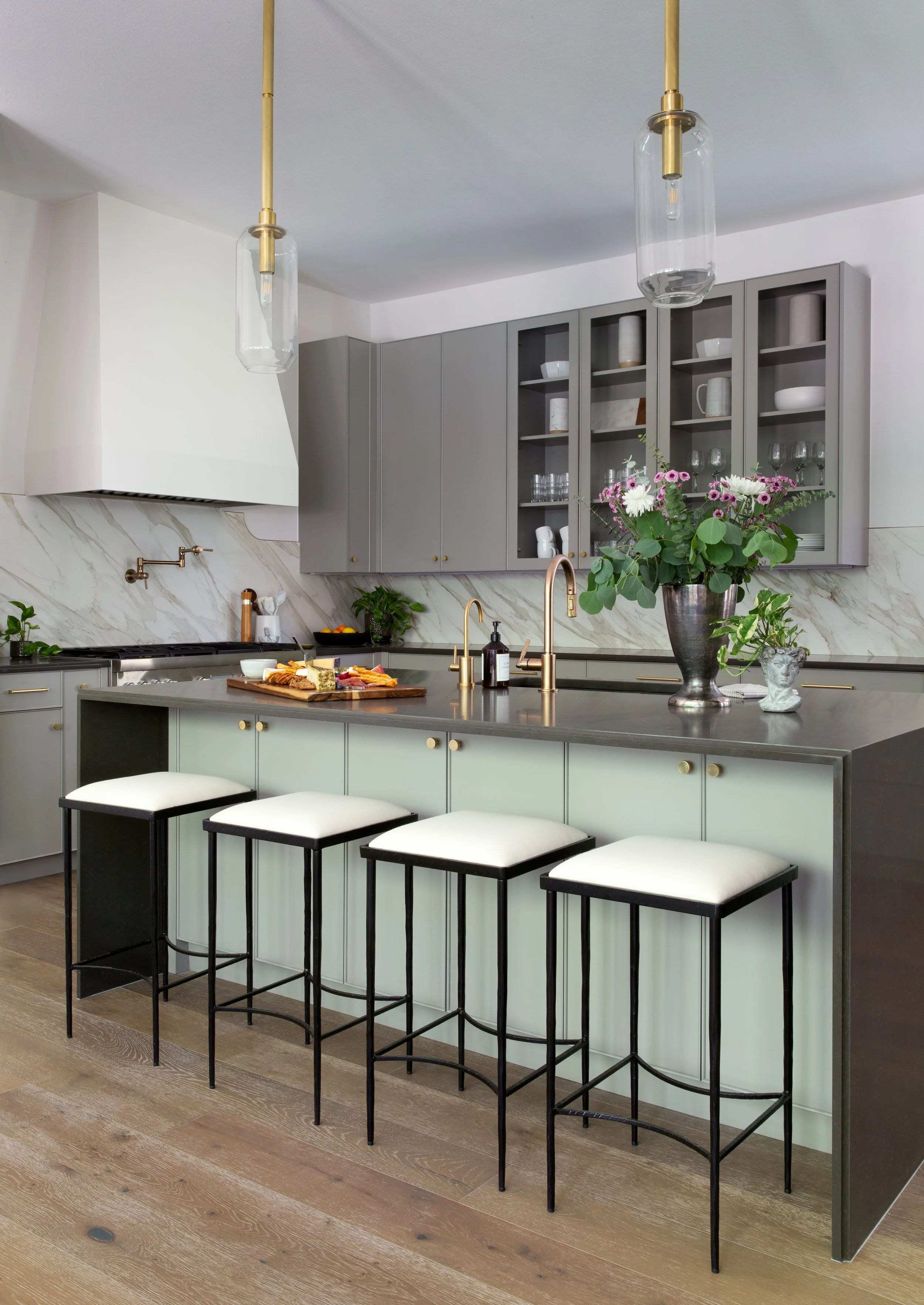 Modern kitchen design with marble backsplash, brass faucet, and island seating