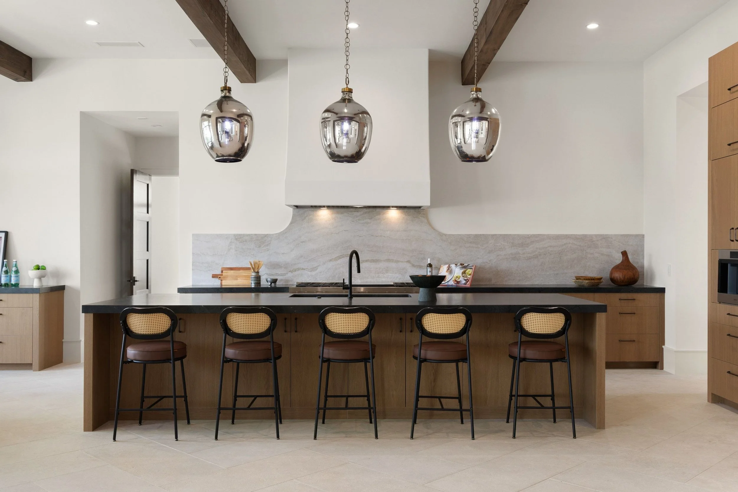 Kitchen island with upholstered bar stools and brass pendant lighting