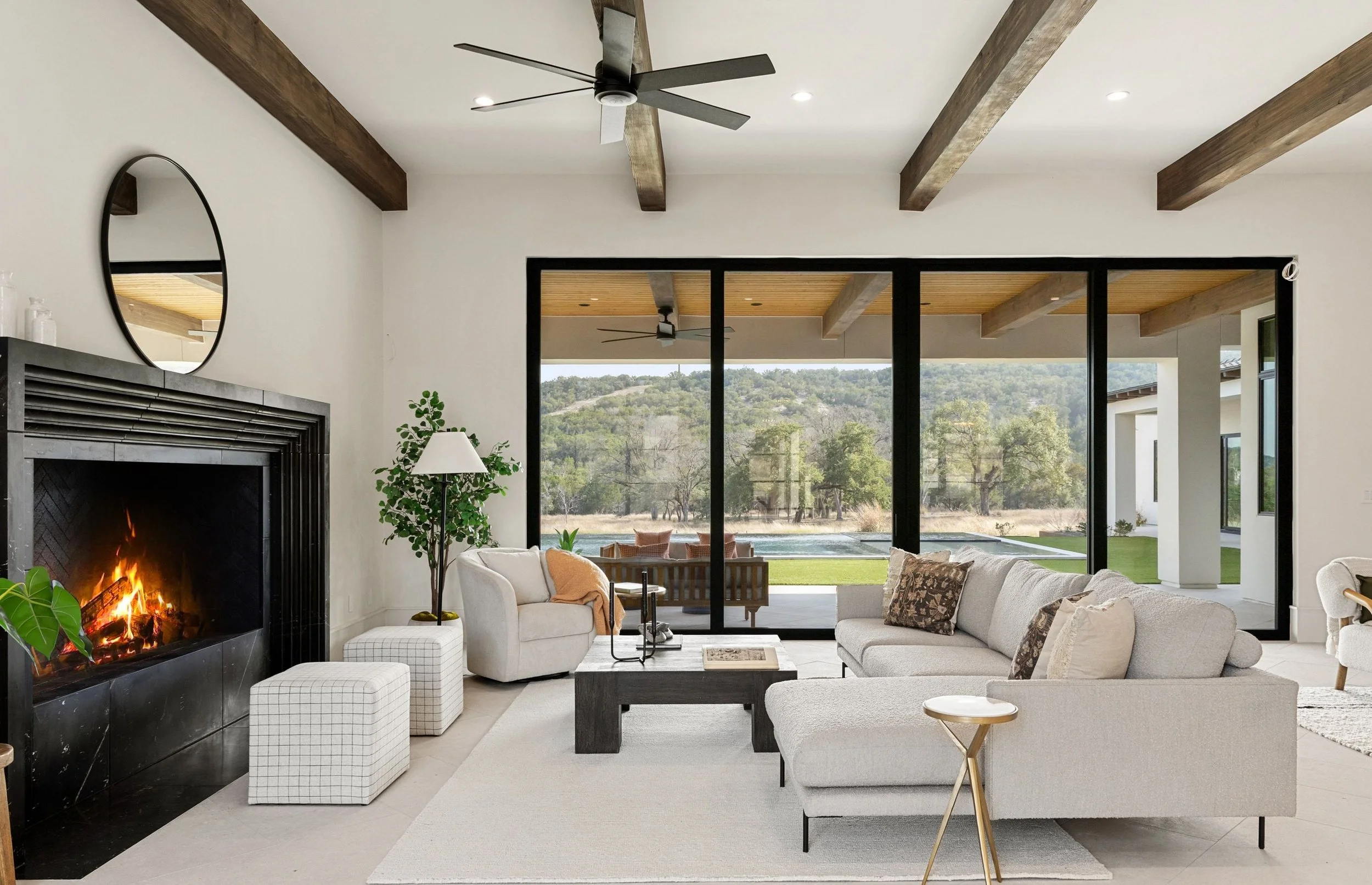 Open-concept living room with fireplace, wood beams, and modern seating