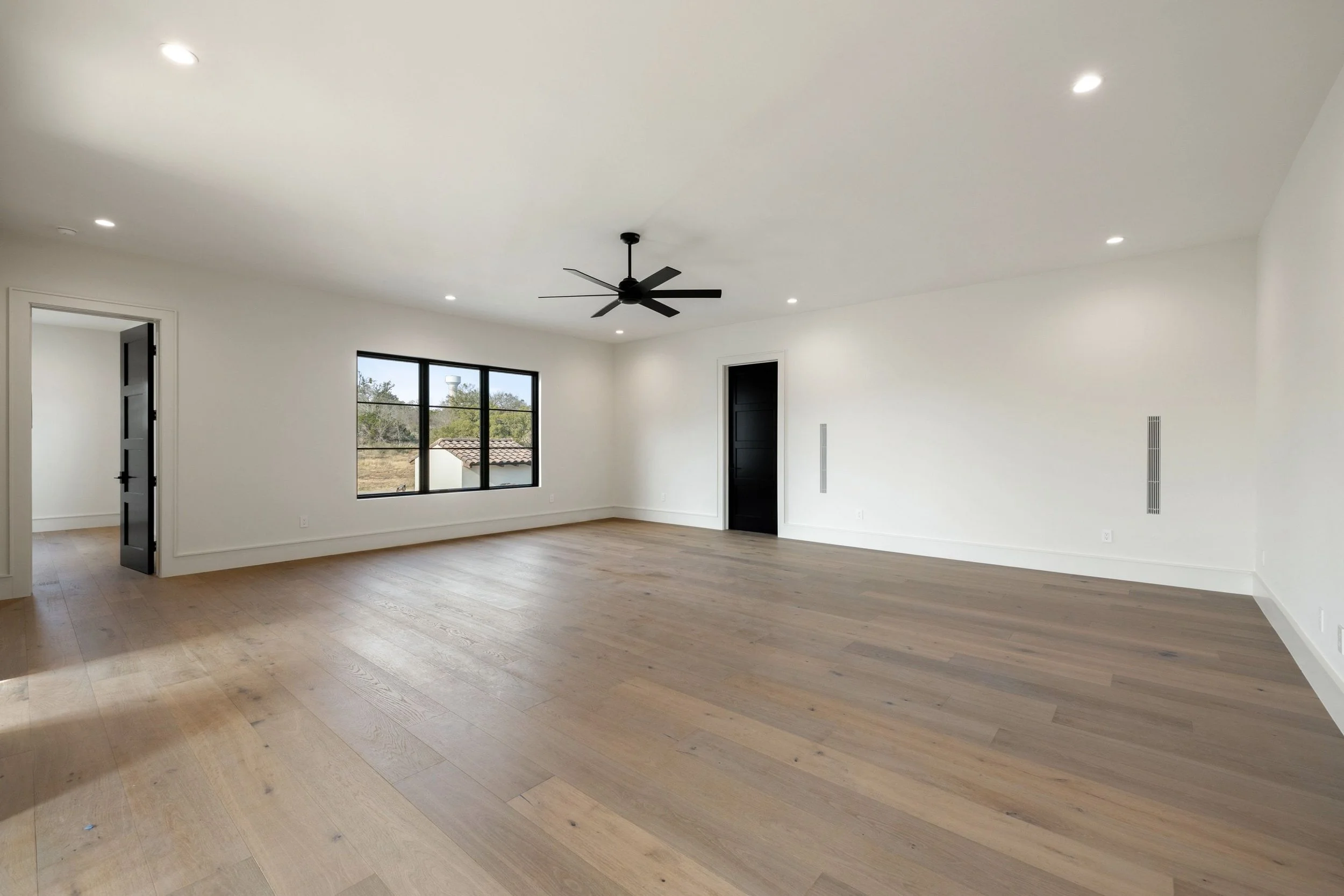 Bedroom with large windows, wood flooring, and ceiling fan