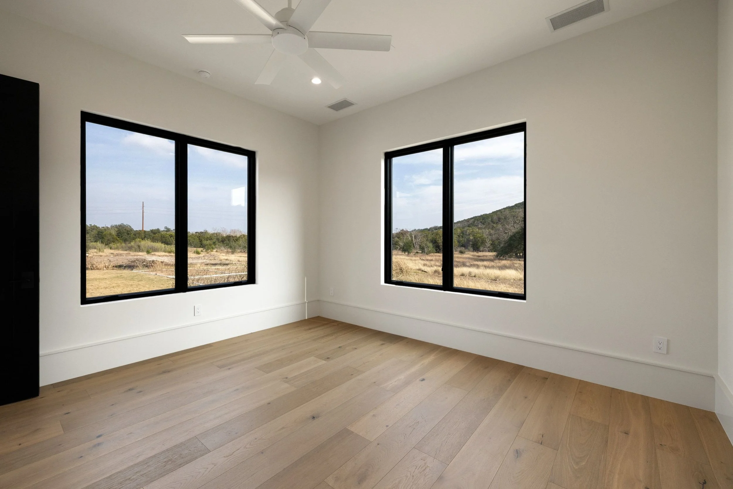 Bedroom with large windows, wood flooring, and expansive view