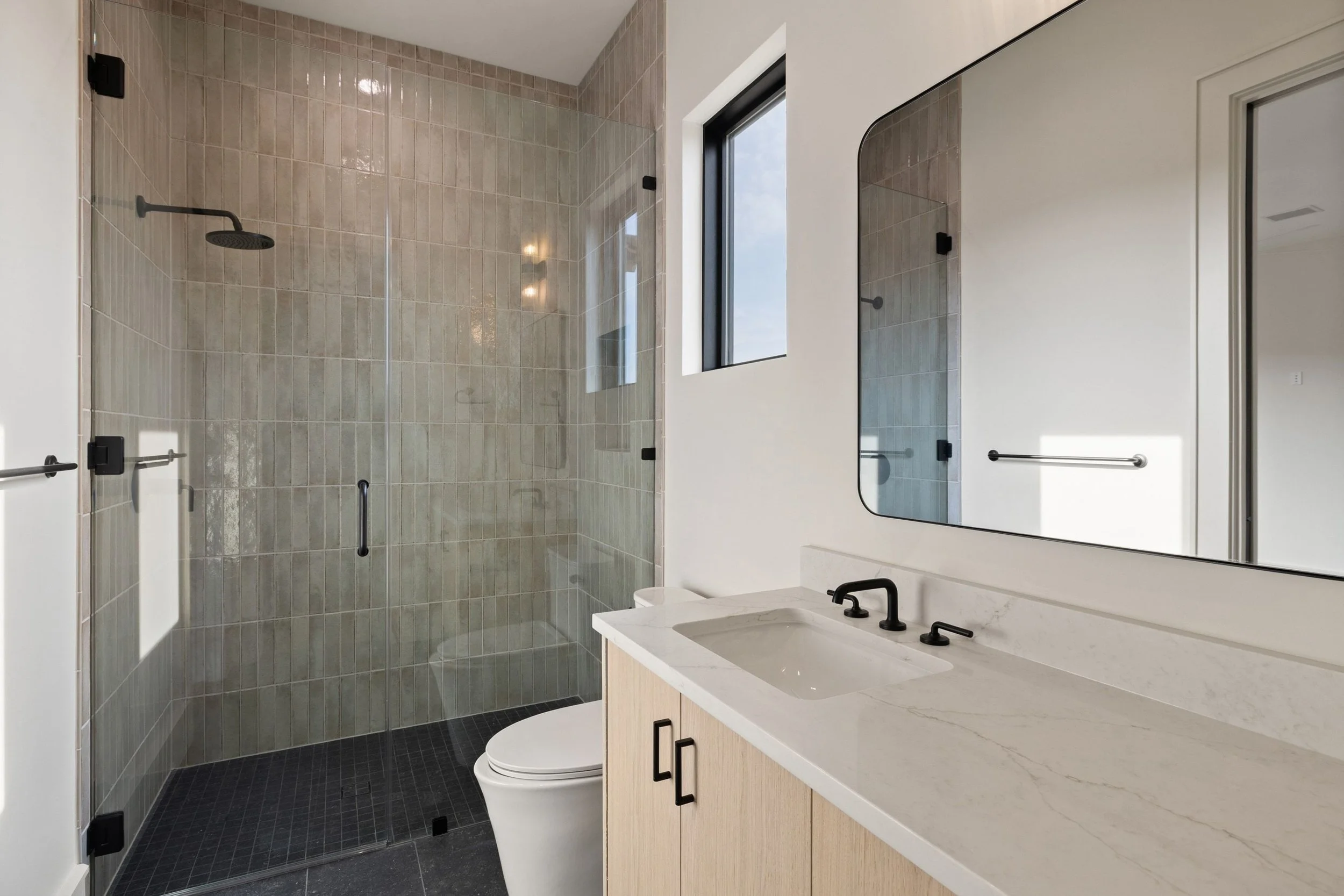 Bathroom vanity with wood cabinetry, vessel sink, and glass shower