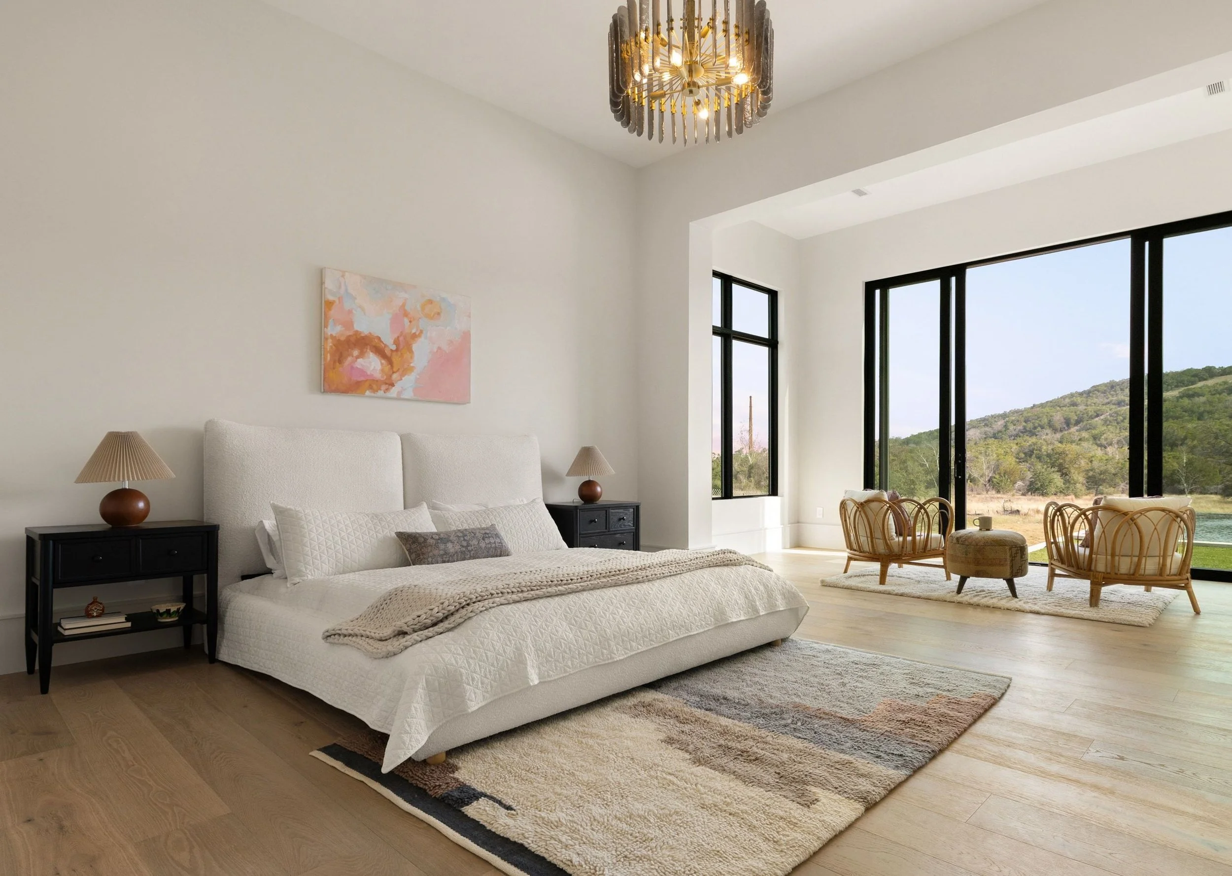 Primary bedroom with upholstered bed, chandelier, and expansive windows