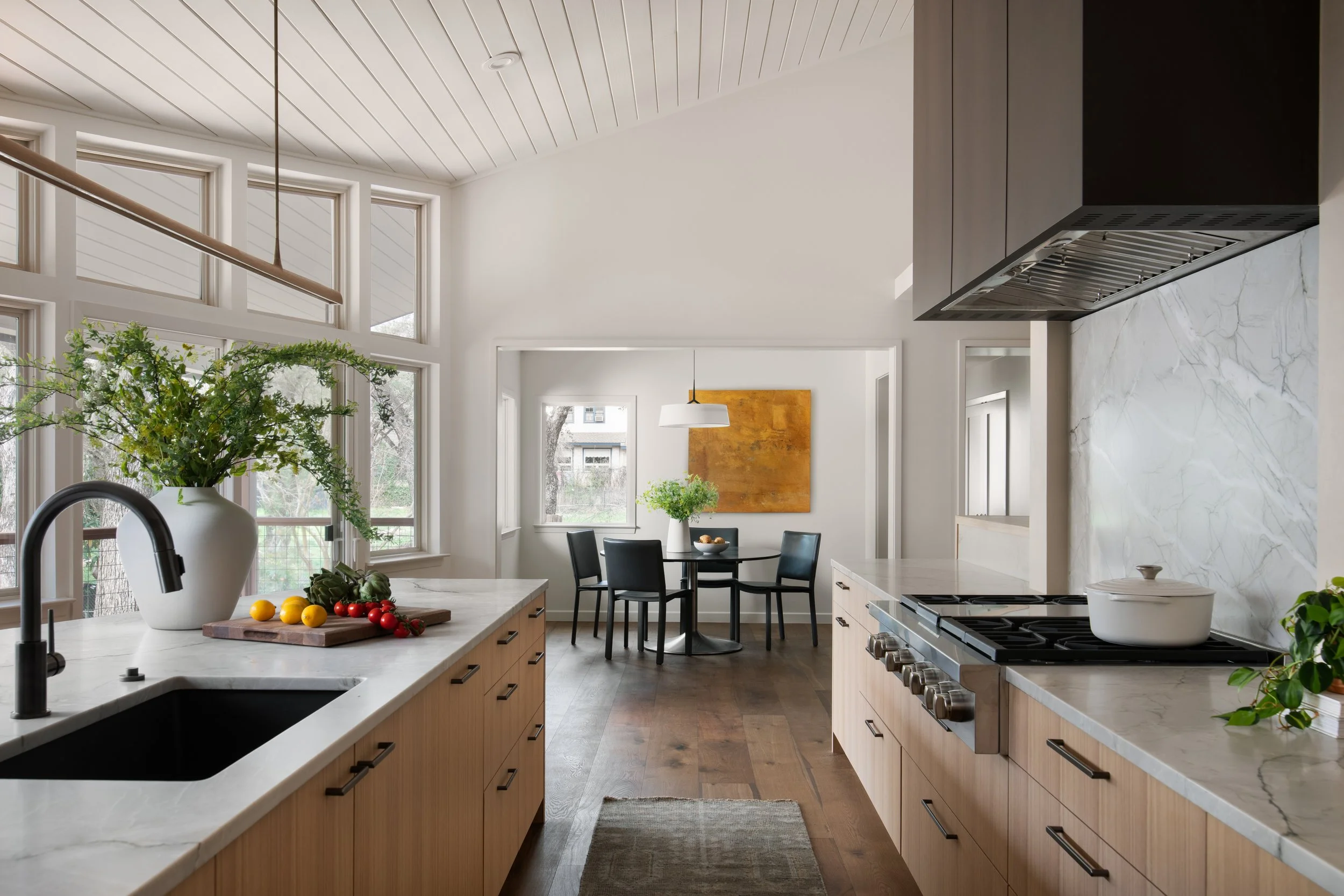 Contemporary kitchen design with marble countertops, wood cabinetry, and open dining area