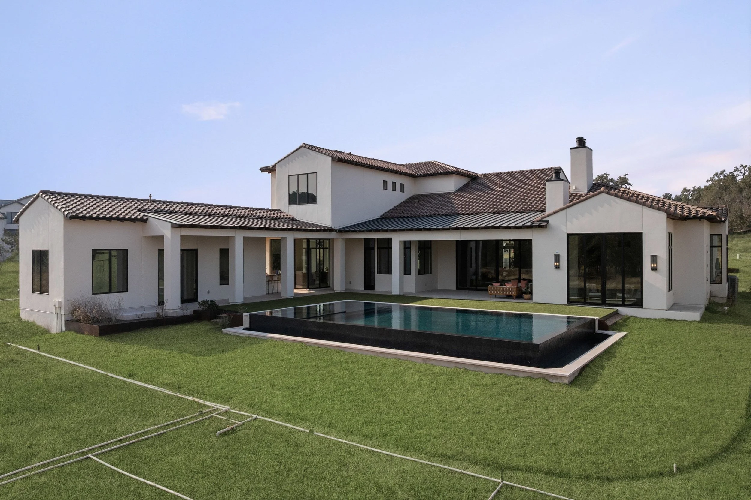 Rear home exterior with covered patio, swimming pool, and landscaped backyard
