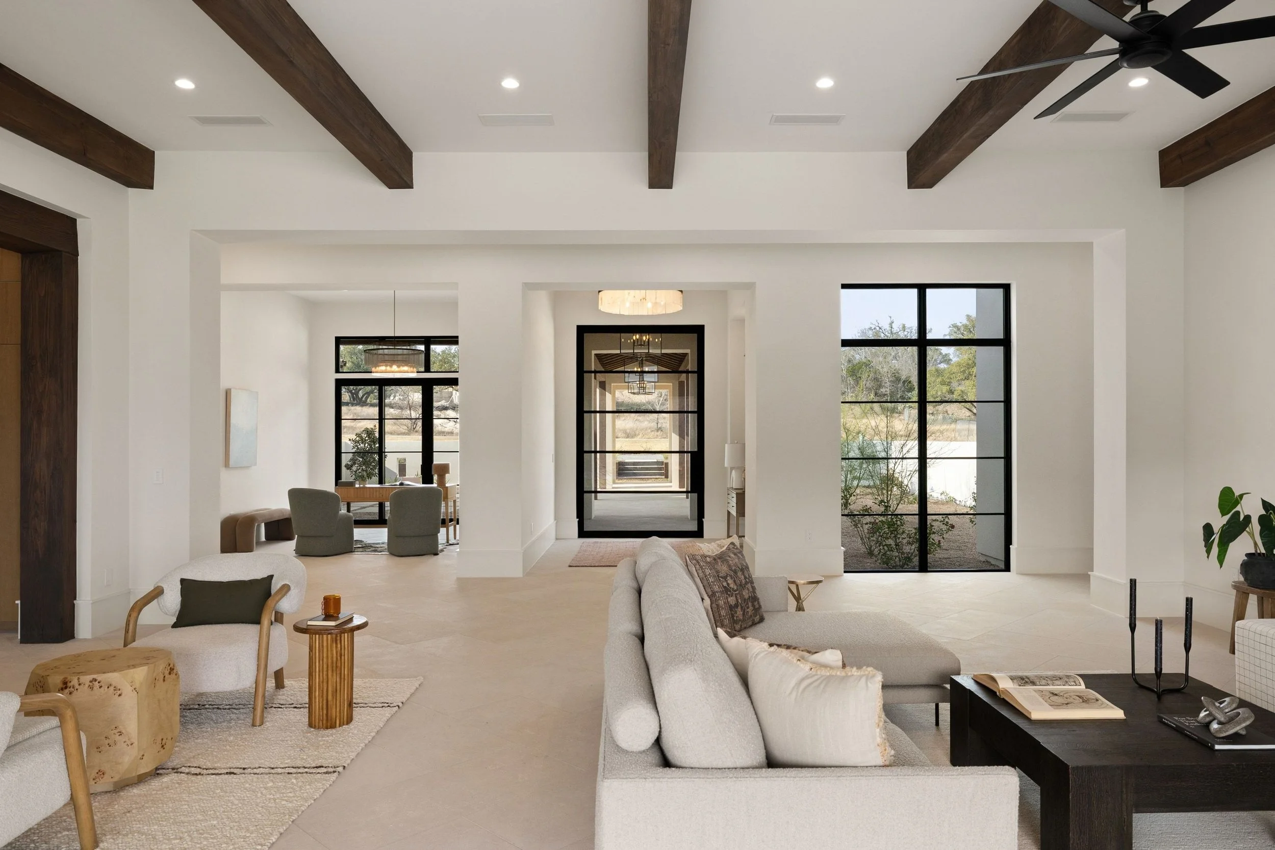 Open-concept living room and entryway, wood beams, and modern seating