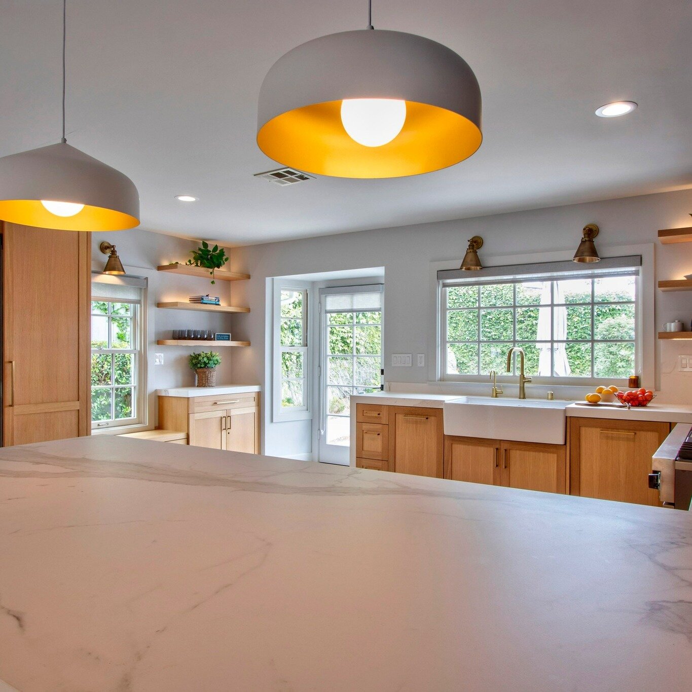 Lighting can make or break a room. Not only do we love these pendants and sconces that provide these homeowners with lots of task lighting, but the floating shelves in the background also incorporate ambient lights to warm up the space and provide th