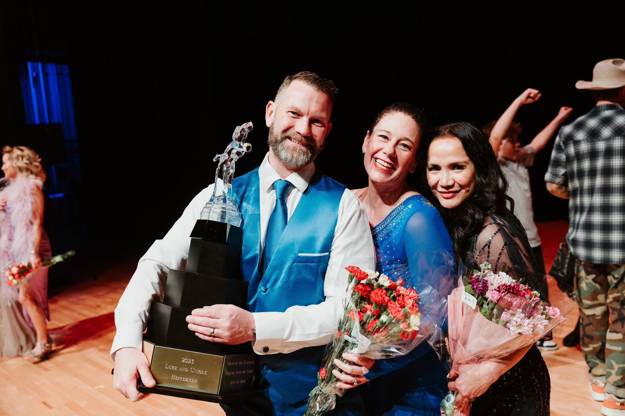 Dancing couple with instructor, trophy and flowers