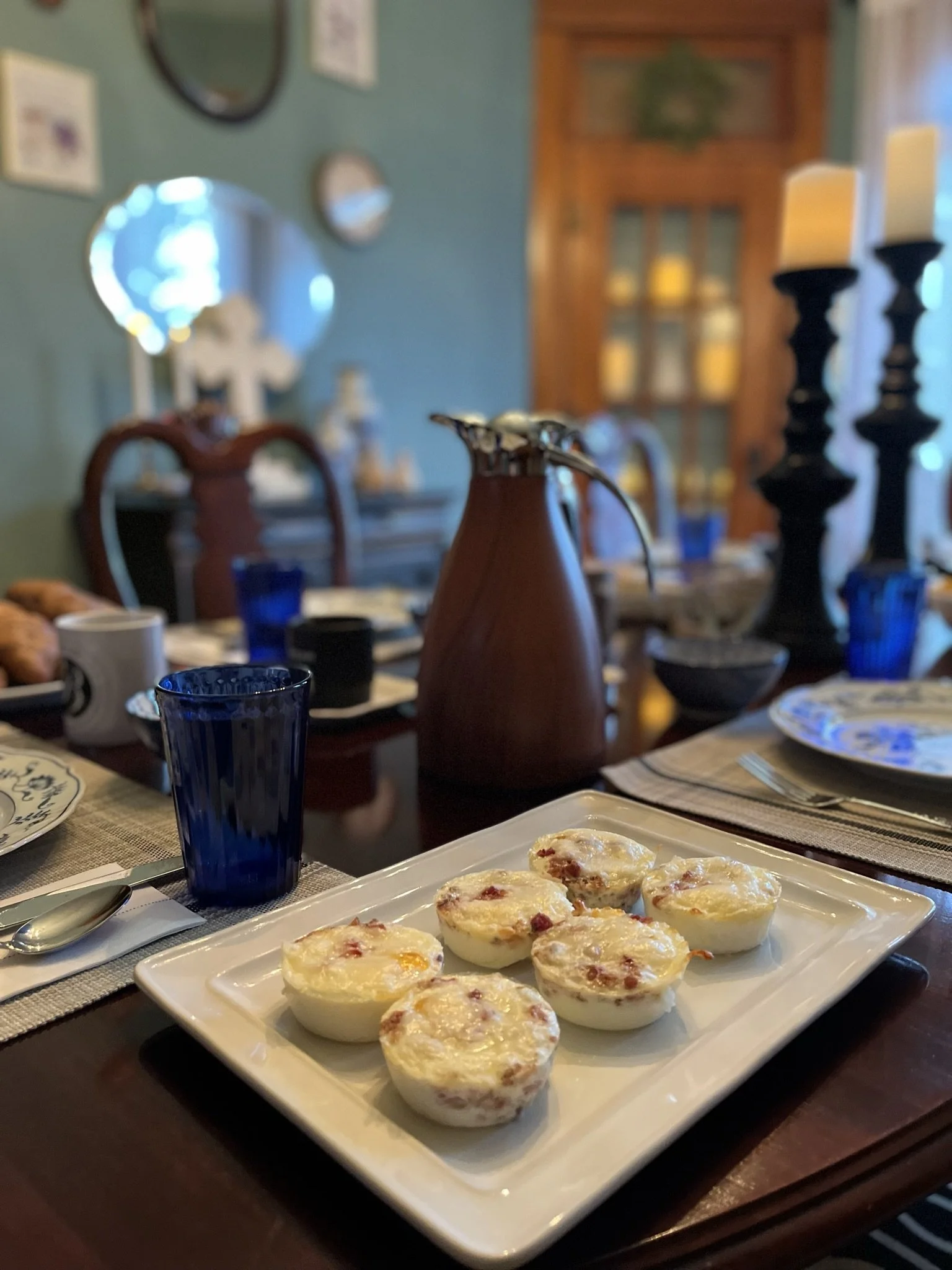 Plate of nine stuffed eggs on a dining table, with glasses and candle holders in the background.
