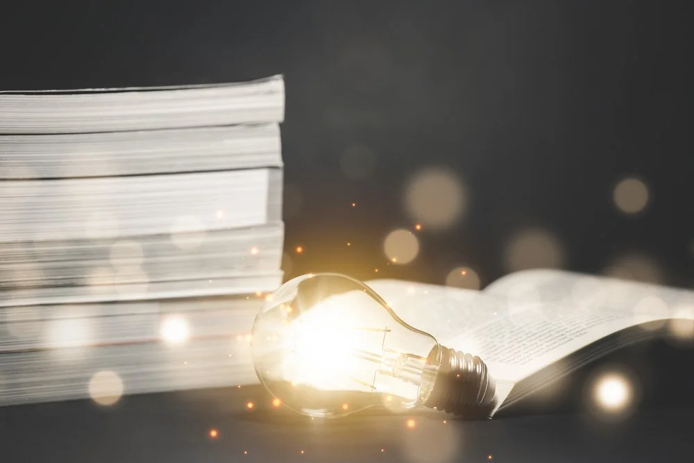 A lightbulb illuminates a stack of manuscripts.