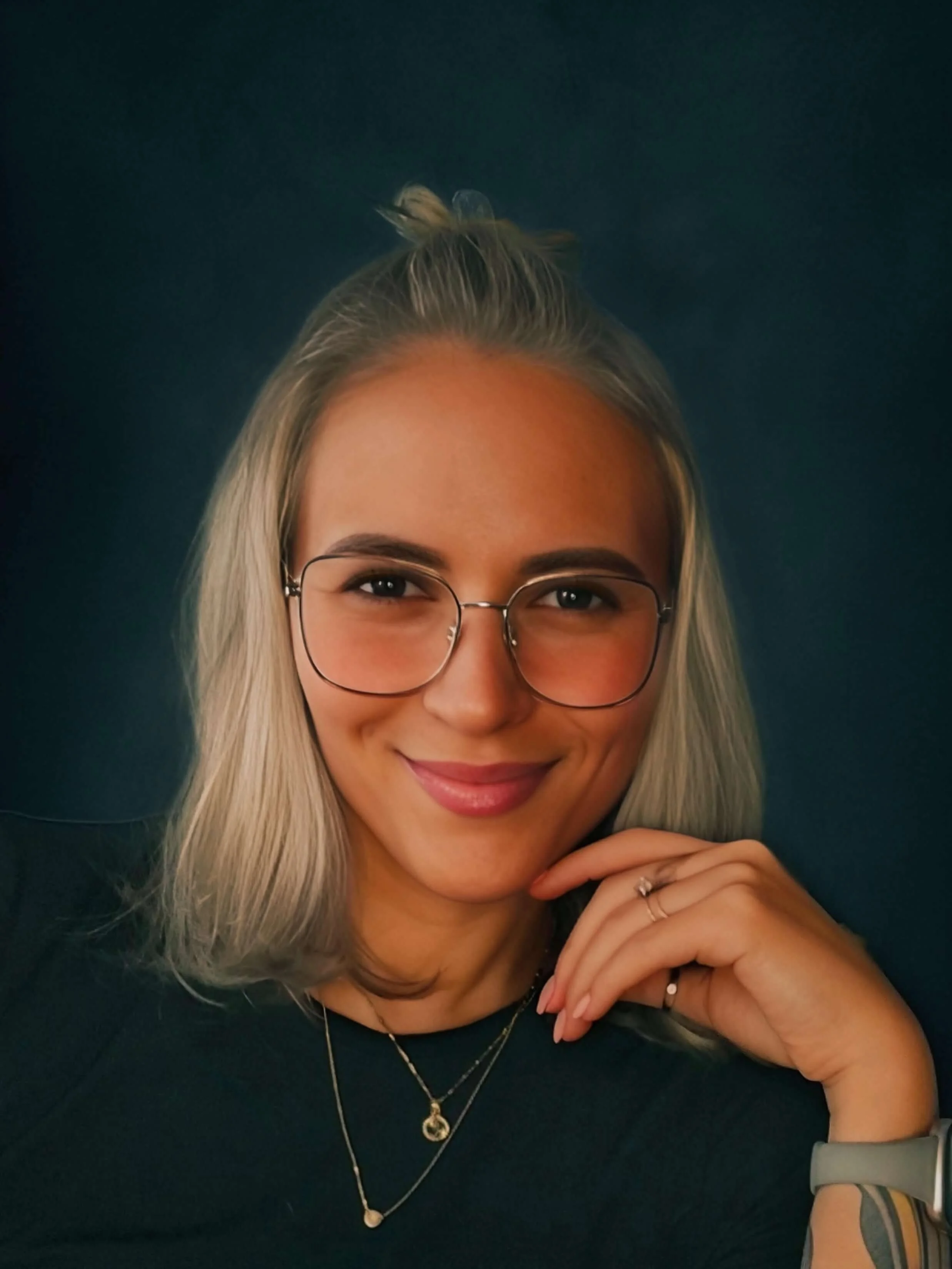 Maddison Dawn, dark fiction author and client of Olivia Bedford, smiles at the camera with her hand resting on her chin.