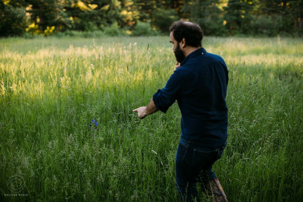 Man pointing at Camas Lily in a field by Melissa Robin Photography