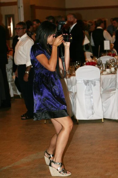 Woman in a blue dress taking a photograph at a formal event.