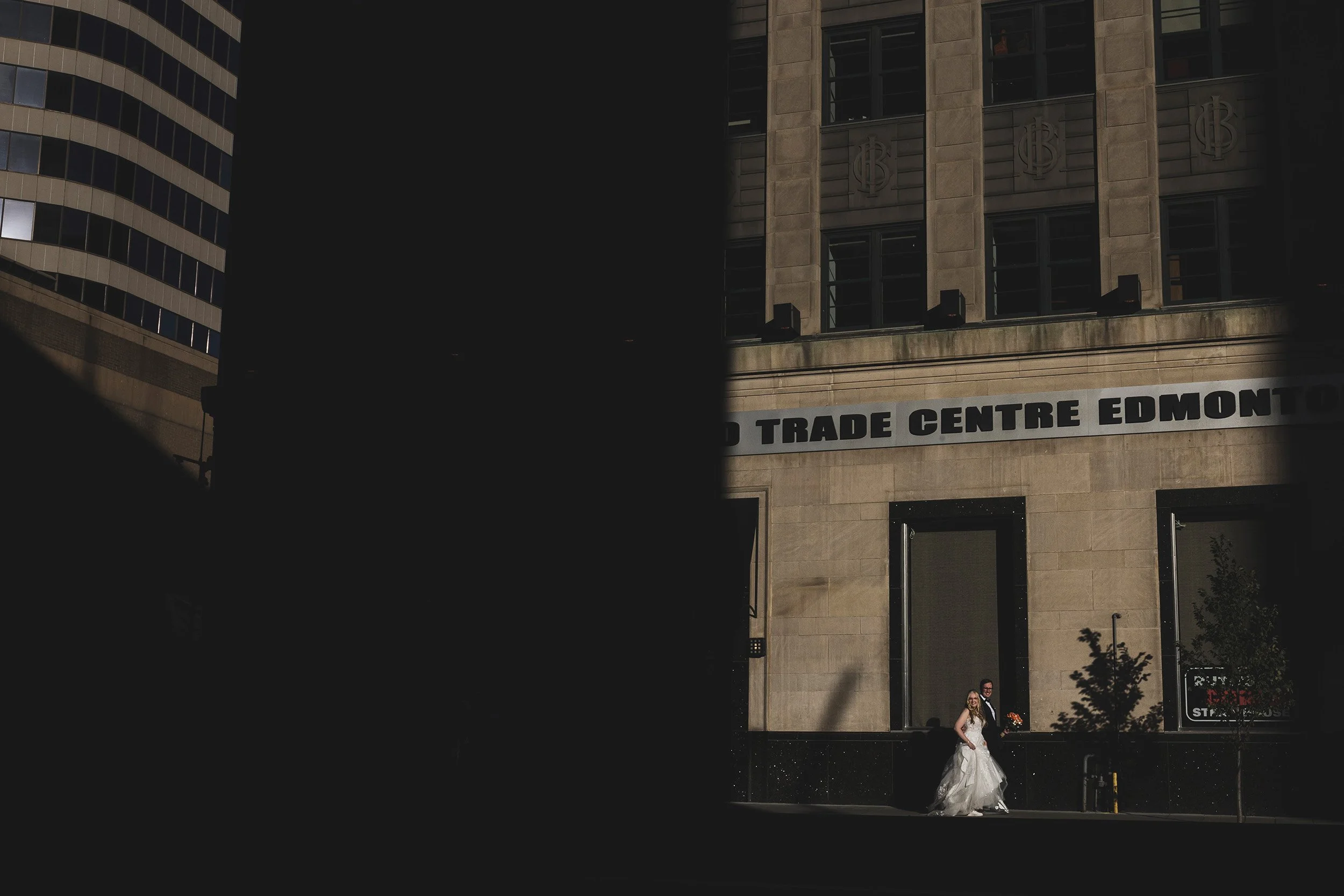 Wedding photography in Edmonton downtown street couple walking in bright sun light. 