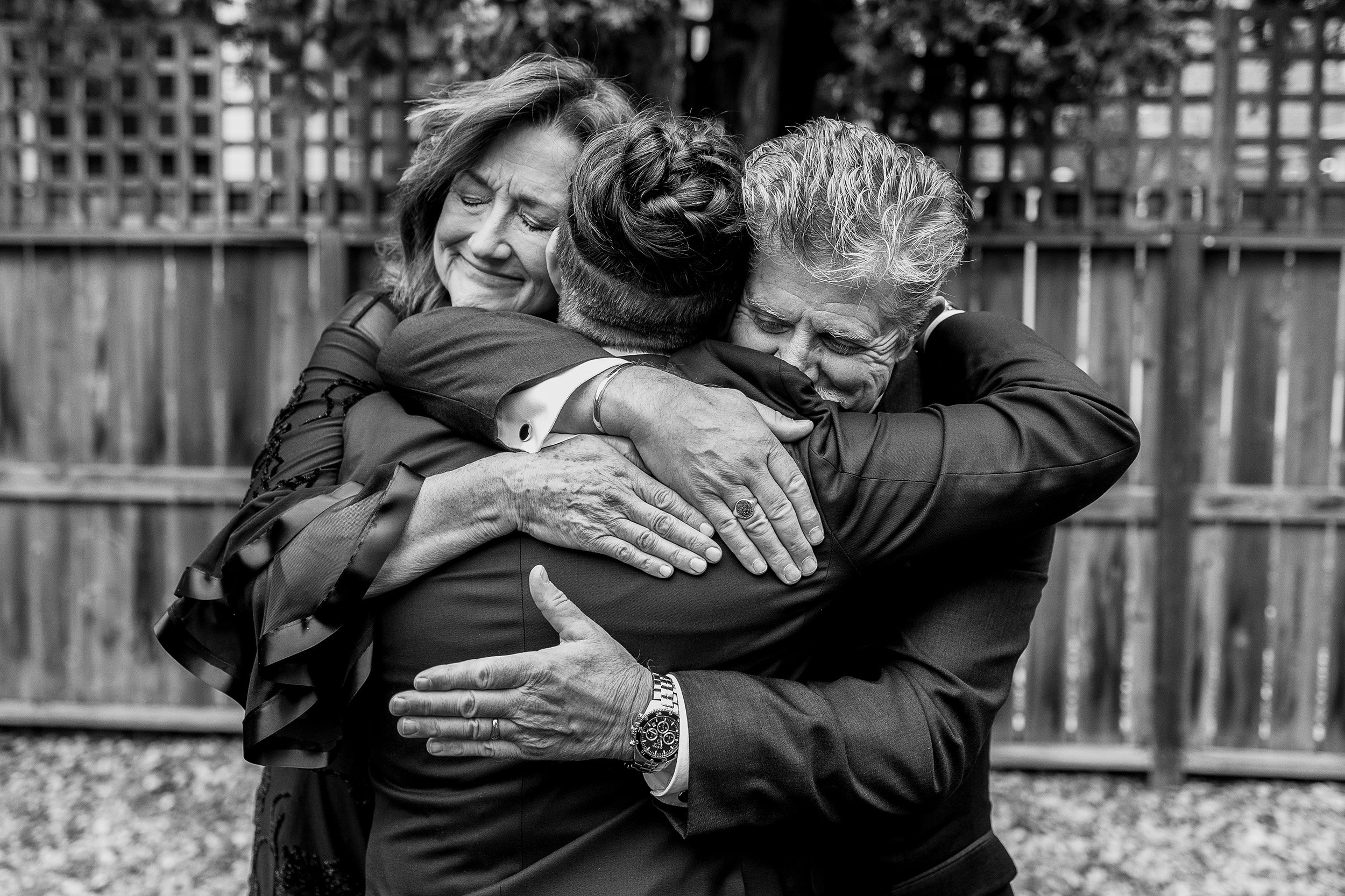 Parents hug bride. Inclusive wedding photography. 
