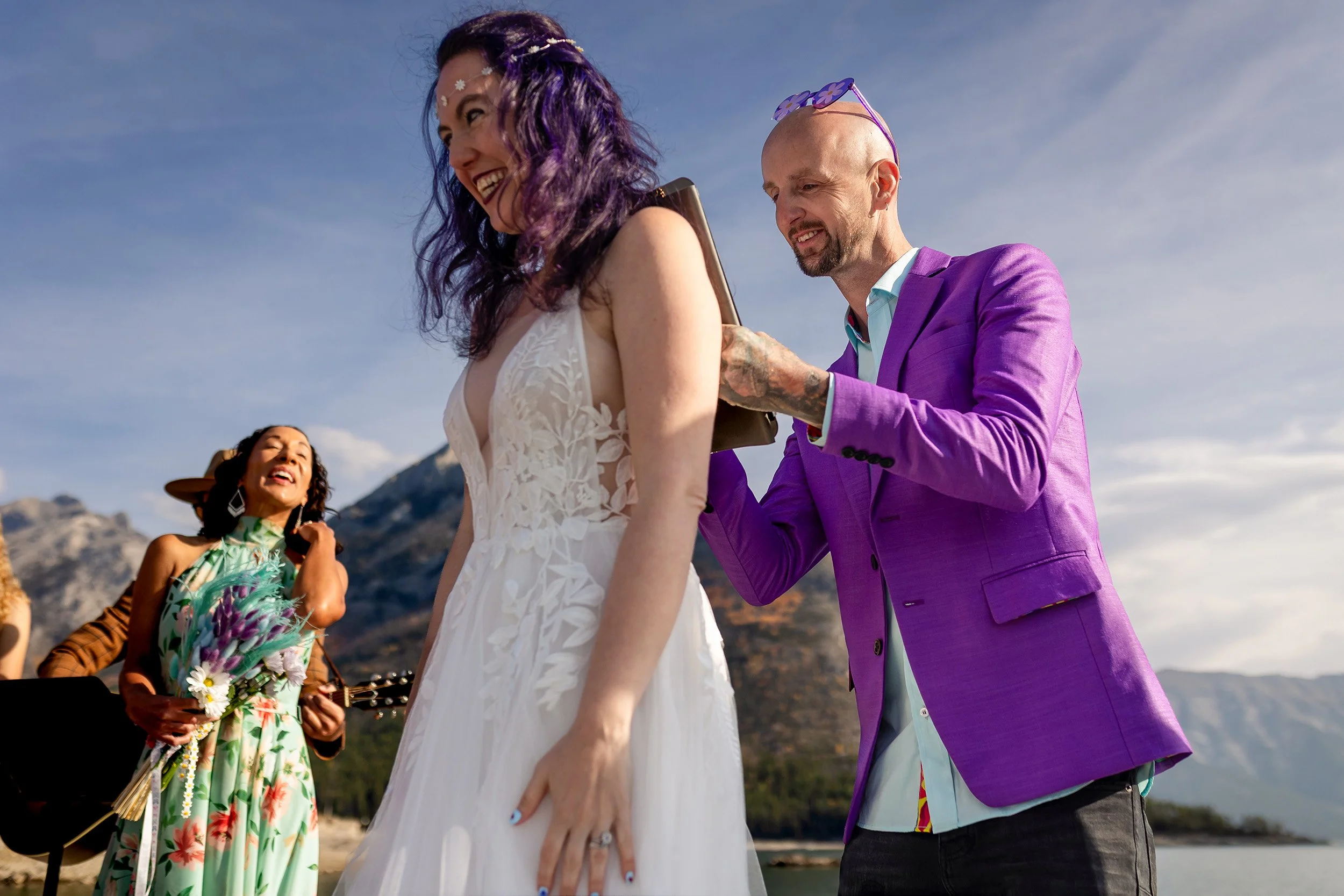 Alt Groom signs on Bride's back during Lake Minnewanka elopement in Banff Alberta