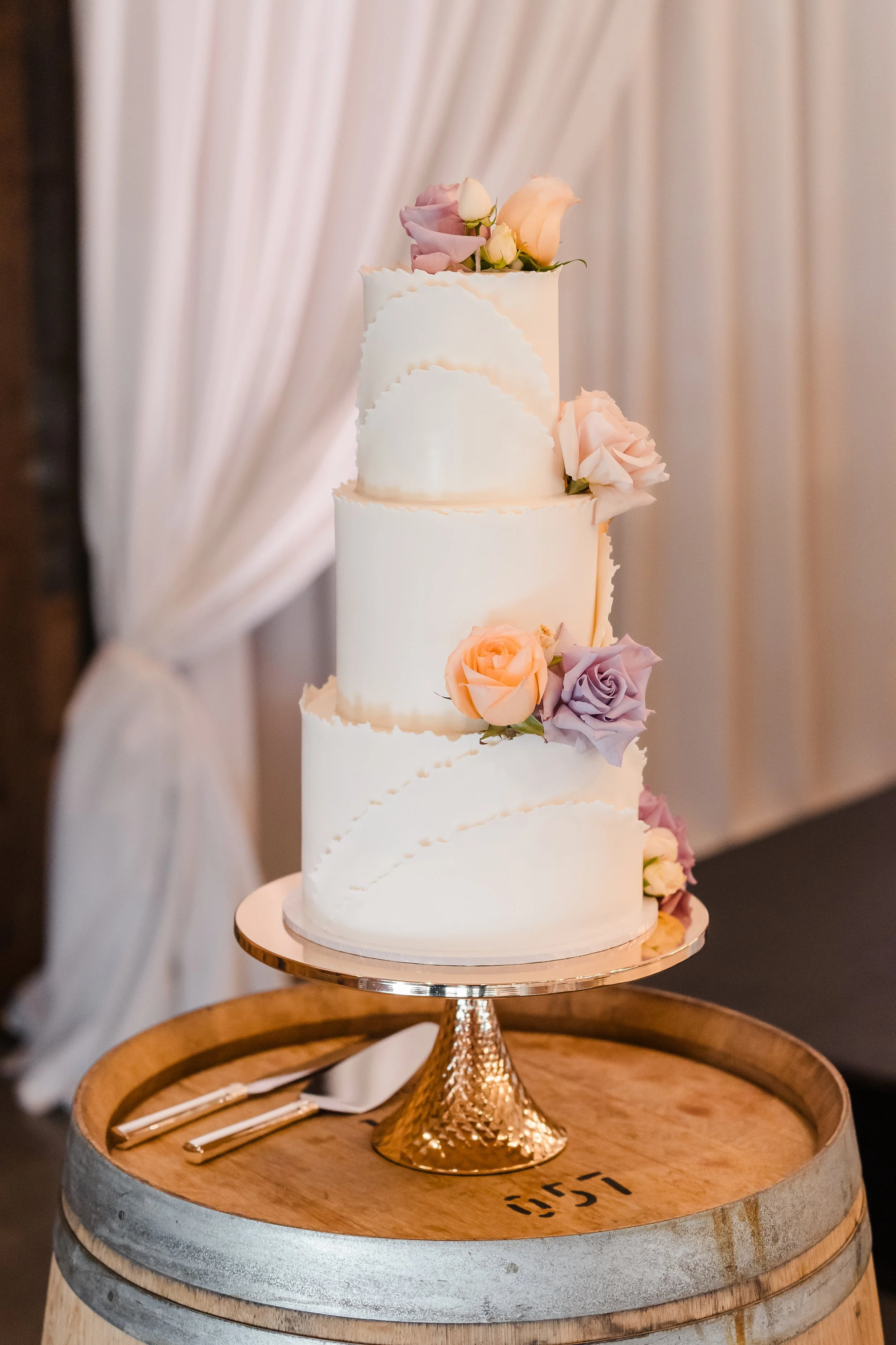 Elegant white, three-tier wedding cake with pastel florals in wine barrel in the Estate Room at Sandalford, Swan Valley