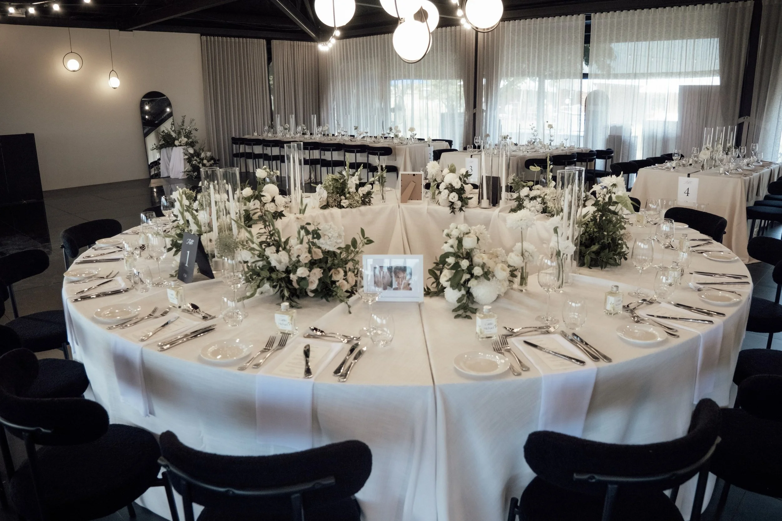 Circular bridal table styling featuring layered white linens, florals and contemporary tableware.