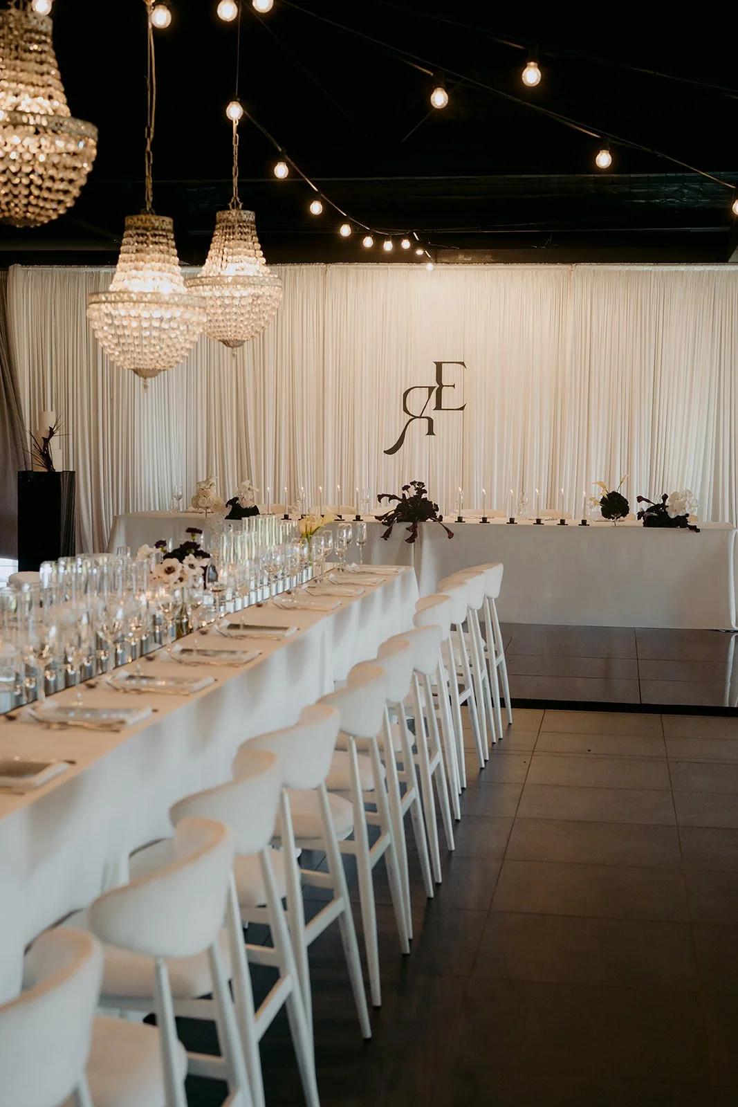 Elegant wedding reception styling featuring draping, chandeliers, candlelight and refined details.