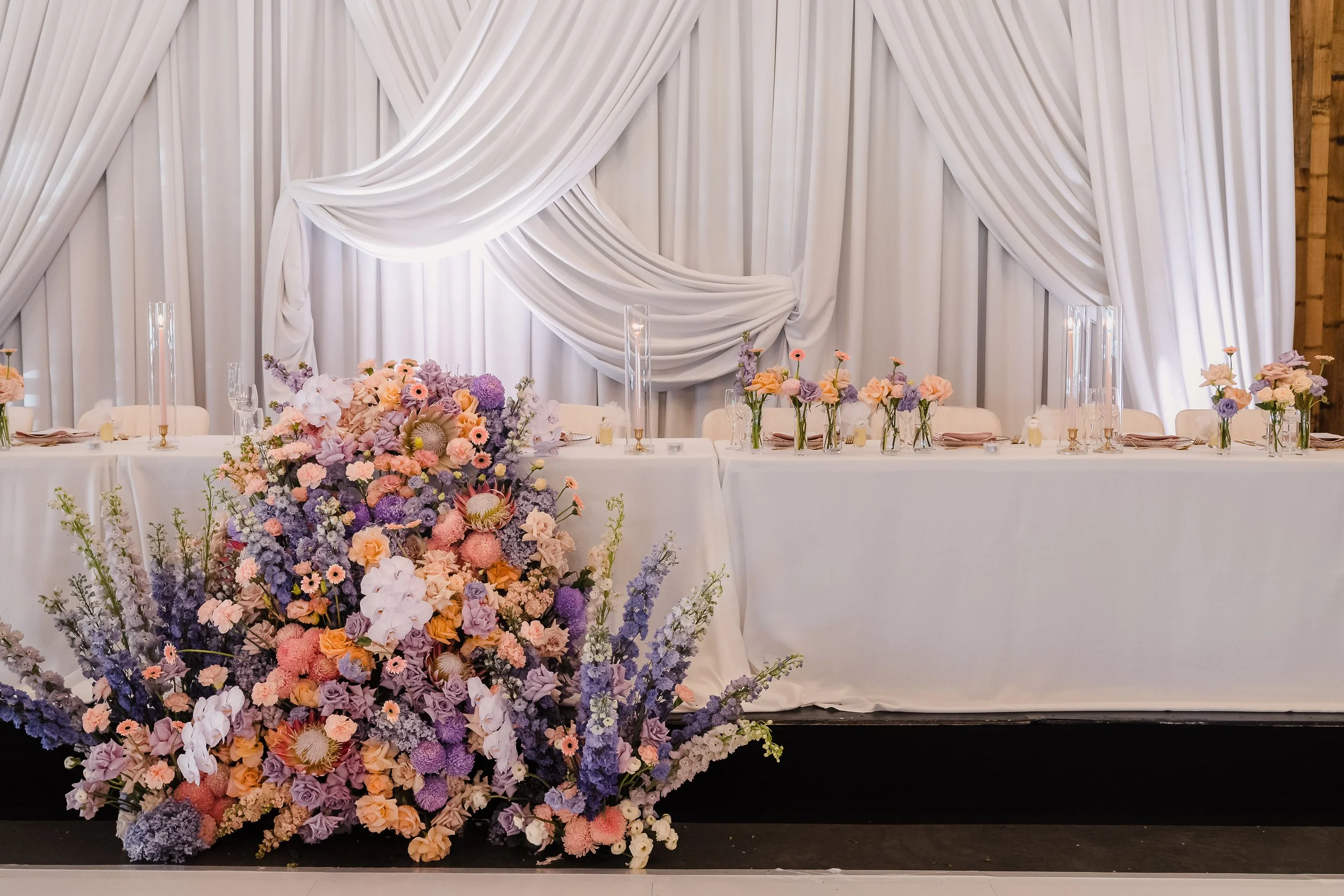 Elegant head table with cascading florals and draped backdrop
