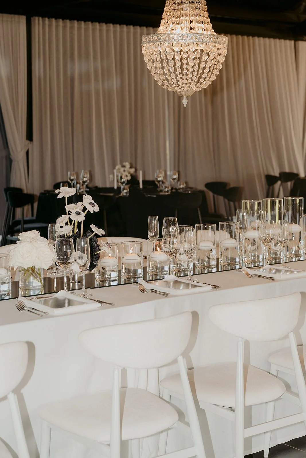 Feature table styling with mirrors, candlelight, florals and chandeliers creating depth and sophistication.