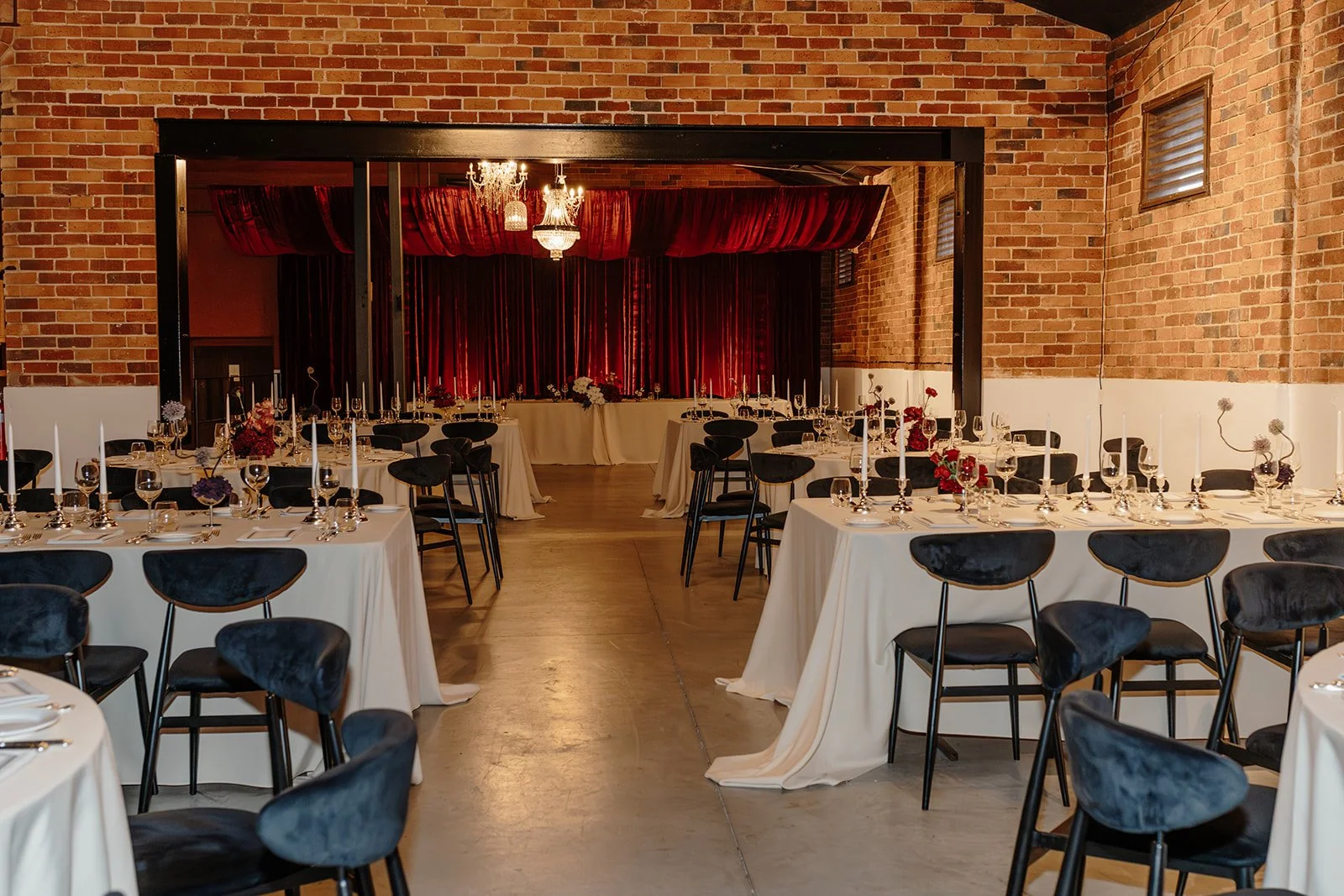 Bold and luxurious wedding reception at Nikola Estate’s Old Cellars in the Swan Valley, featuring dramatic red draping, black velvet chairs, and a taupe, deep purple, and red colour palette for an elegant 80-guest celebration.