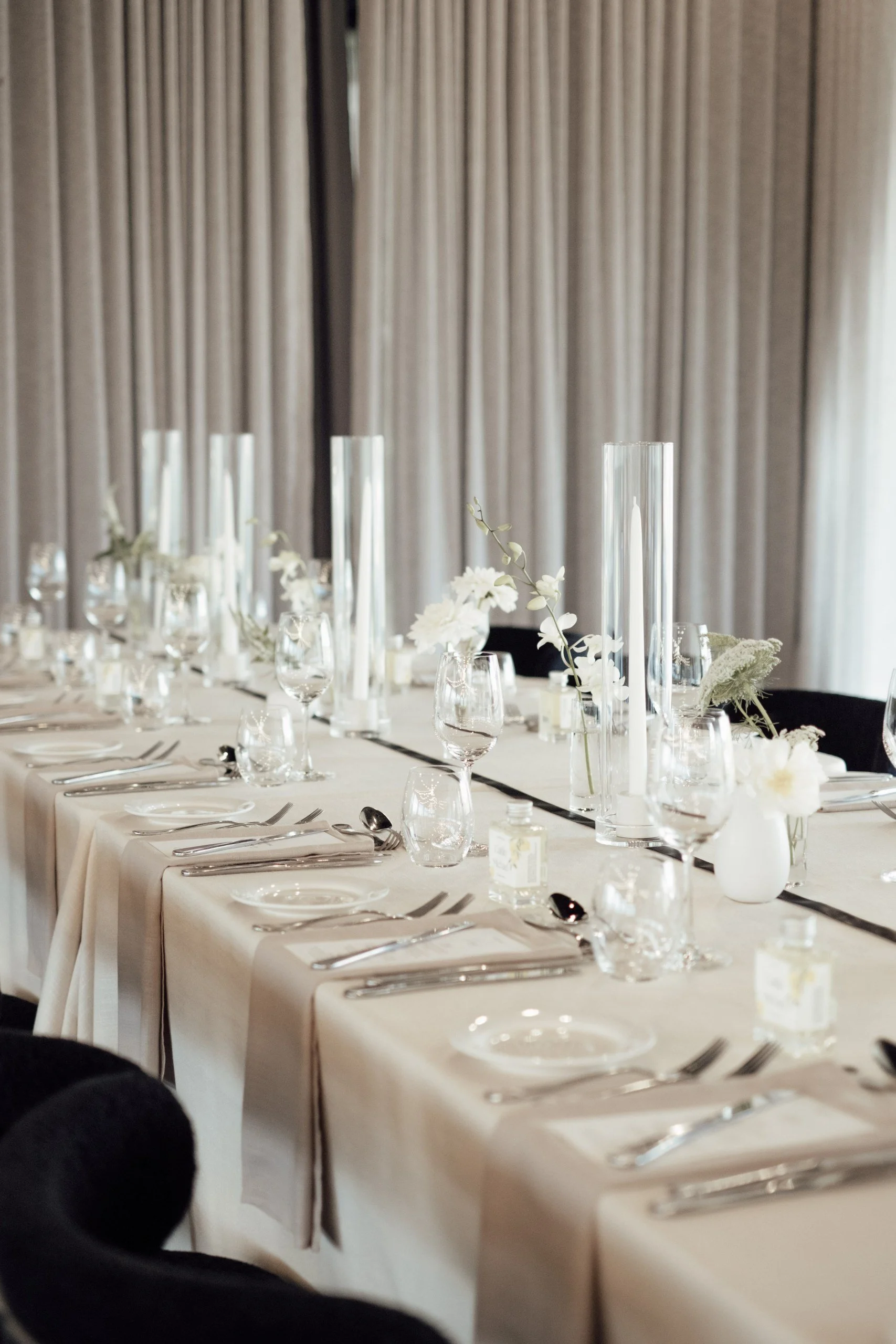 Contemporary guest table styling with neutral linens, florals and candles, black accents.