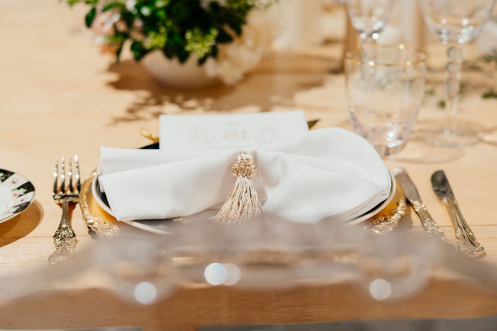 Romantic place setting, luxury place setting, vintage gold charger, vintage blue, gold and white bone chine, gold ornated cutlery, white serviette in bow tie fold with gold tassel, white and gold wedding menu, gold rimmed glasses with floral etching,