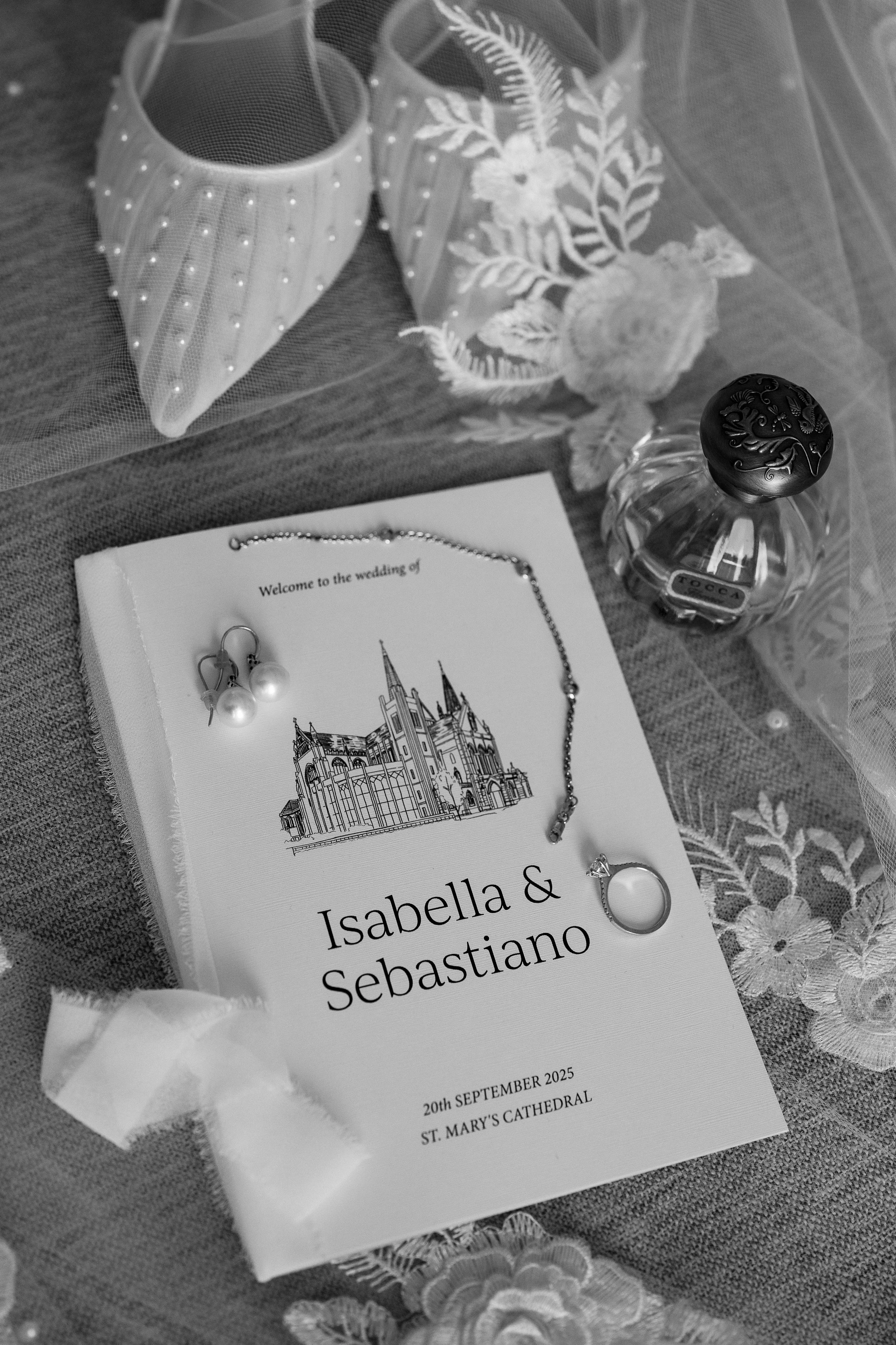 Wedding flat lay with bride's shoe, perfume, wedding ring, veil and custom ceremony booklet with hand-drawn illustration of St Mary's Cathedral