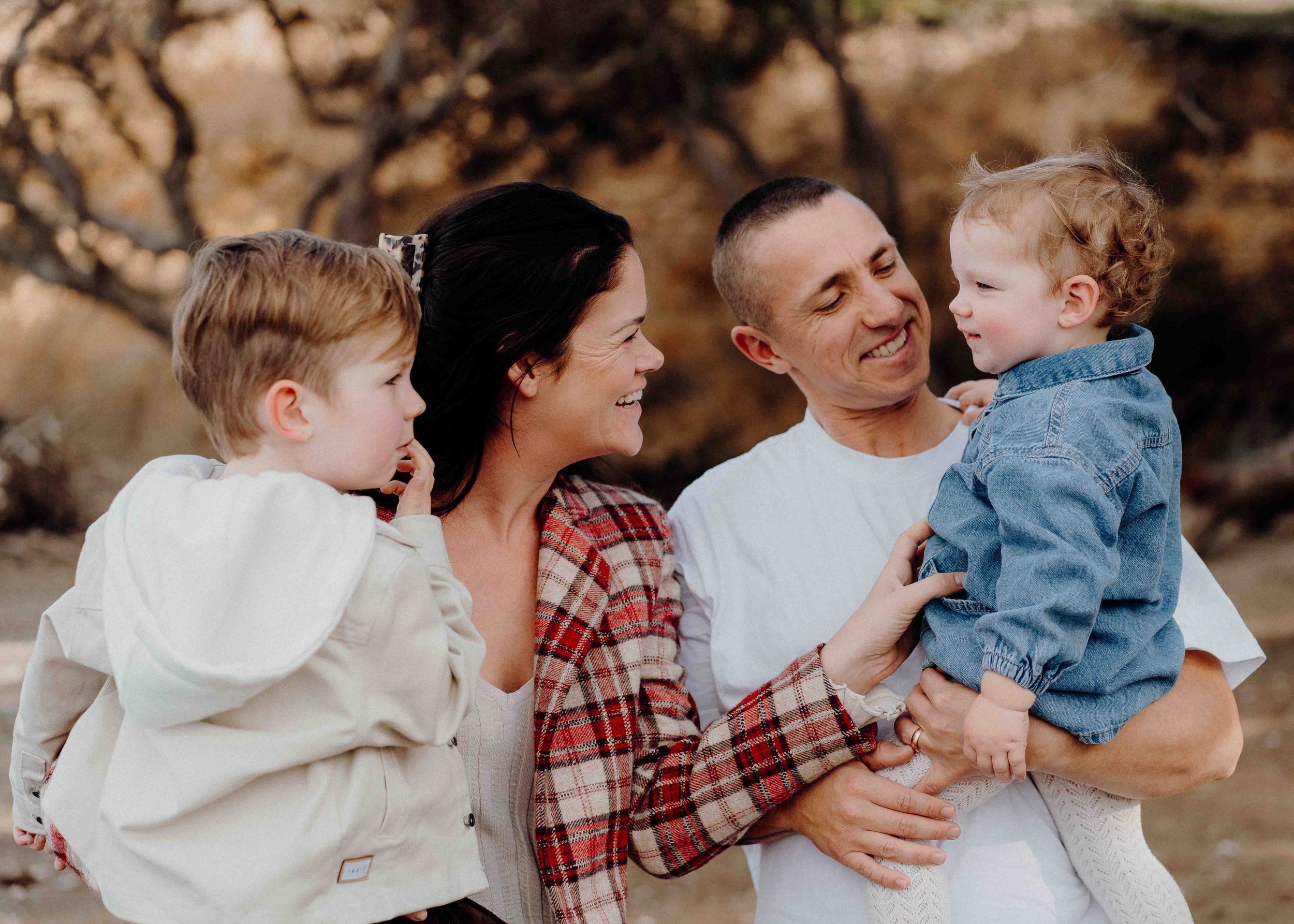 Family with two children outdoors, smiling and interacting.