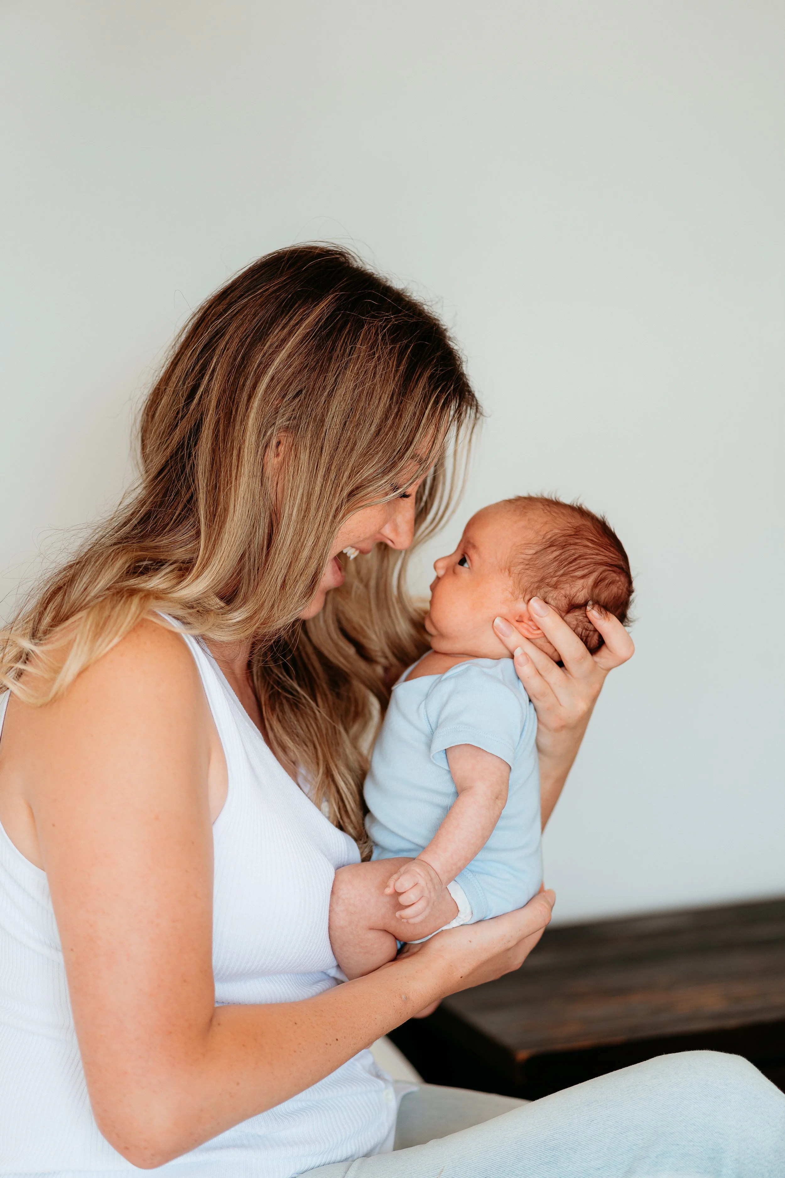 Woman holding a newborn baby close to her face, smiling.