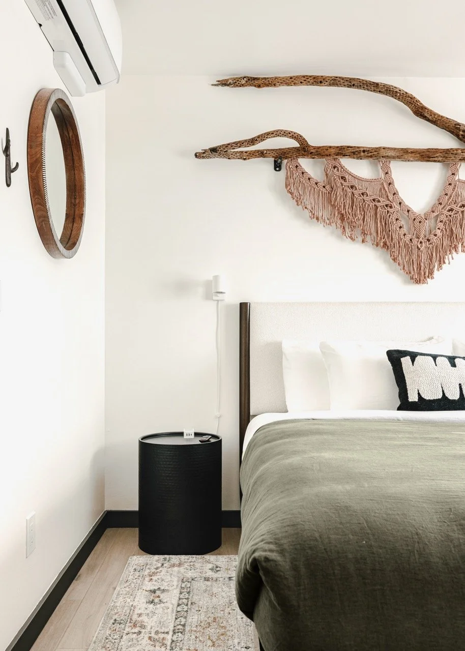 Guest bedroom with a king bed, handcrafted desert-inspired wall art, bedside lighting, and soft neutral furnishings designed for a comfortable night's sleep.