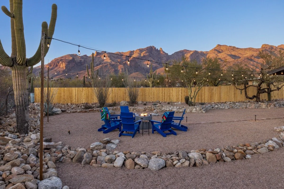 The backyard view at The Copper Burro vacation home with a fire pit, towering saguaro, and dramatic views of the Catalina Mountains