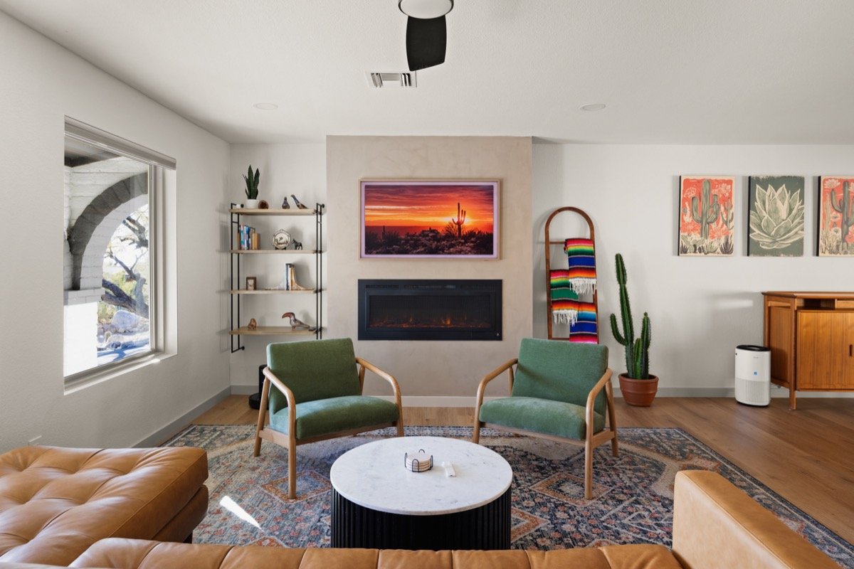 Open-concept living room with a fireplace, two accent chairs, a sectional, and large windows bringing in natural light.