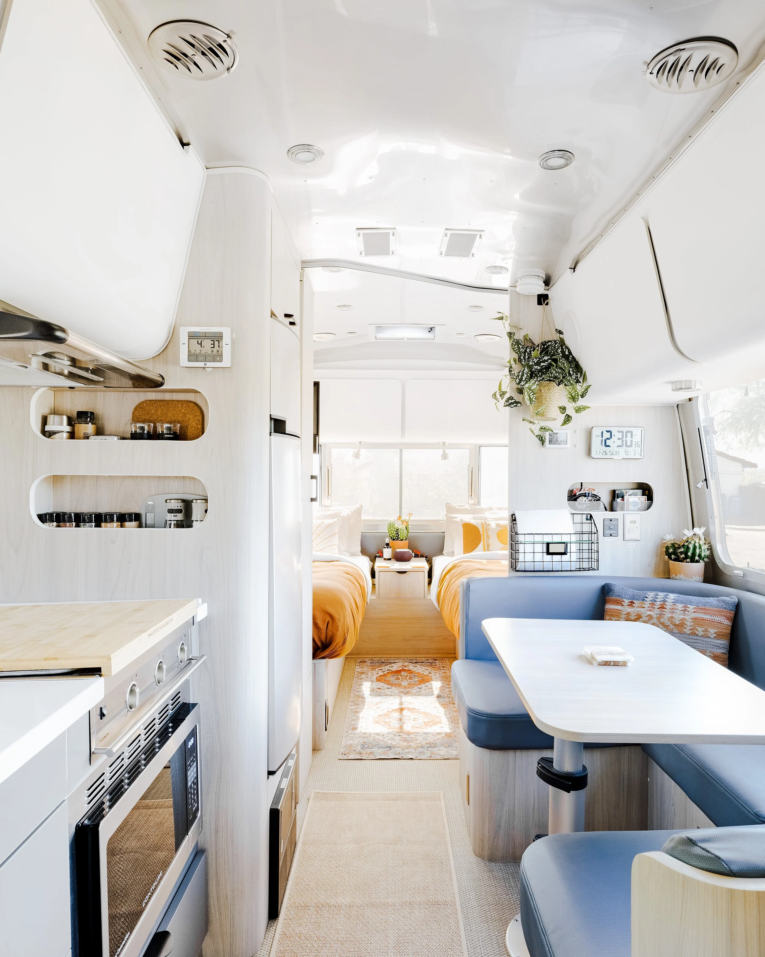 Interior of the Airstream showing the dinette seating area, galley kitchen, and view toward the sleeping area.