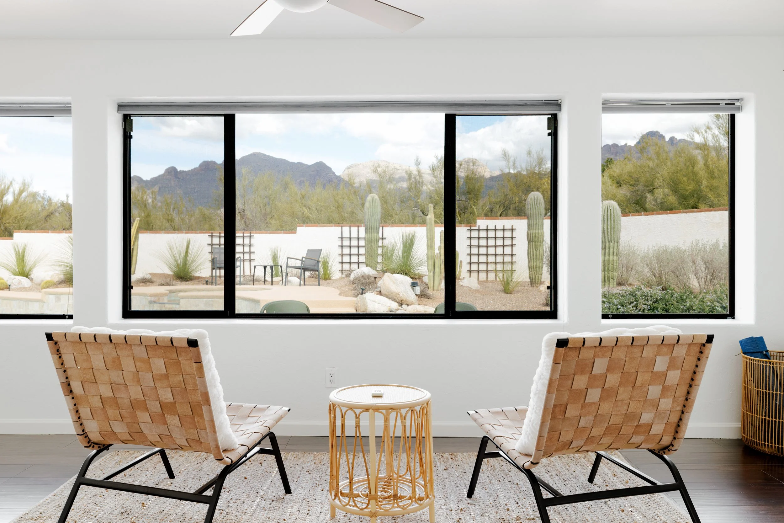 Arizona room with bright light,  accent chairs facing large picture windows overlooking the backyard and Catalina Mountains.