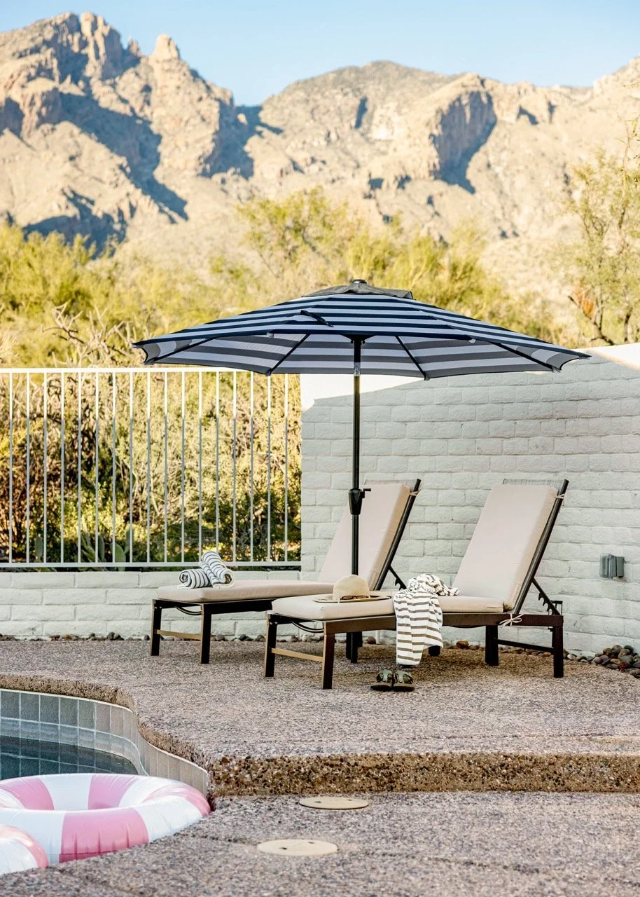 Private backyard with a heated pool, shaded lounge chairs, umbrella, and Catalina Mountain views, creating an outdoor retreat in the Catalina Foothills of Tucson.