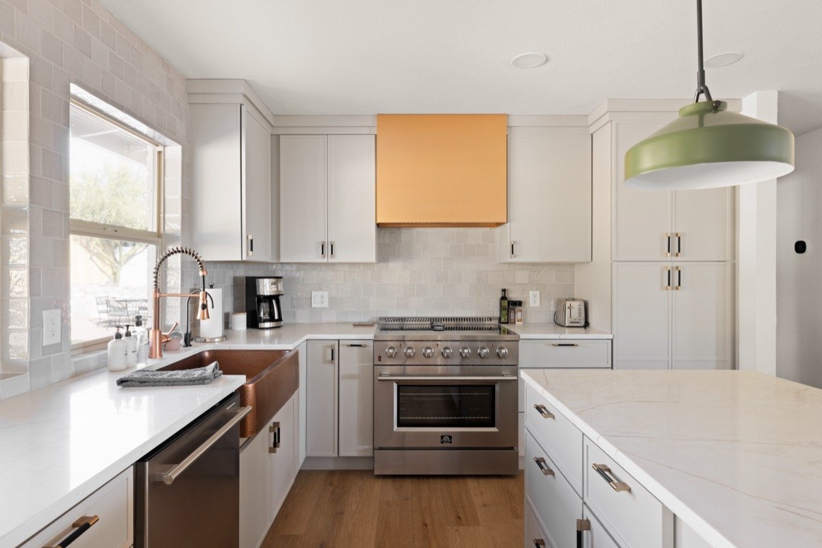 Bright kitchen with white cabinetry, a six-burner electric range, spacious island, and quartz countertops for cooking and gathering.