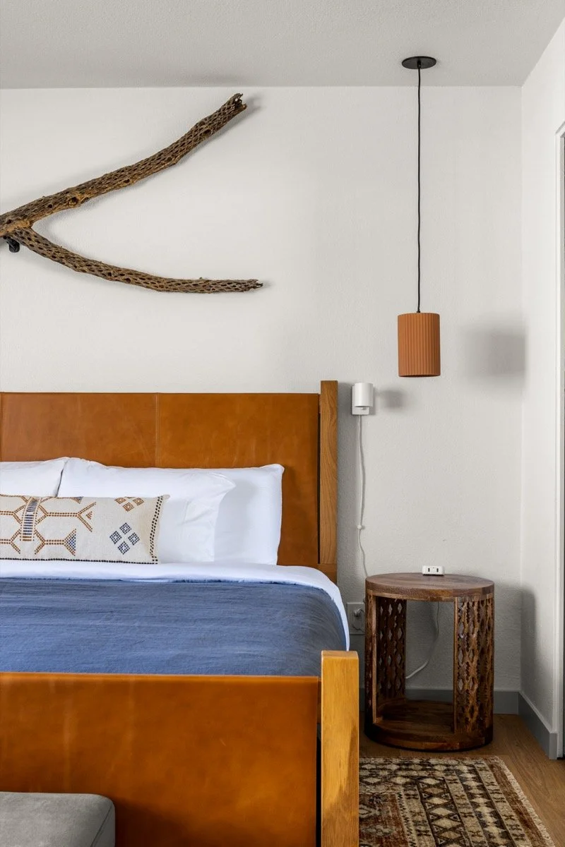 Primary bedroom with a king bed, leather headboard, wood accents, pendant lighting, and an ensuite bathroom.