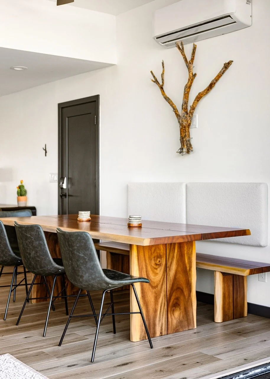 Dining area with a live-edge wood table, accordion glass doors, and Catalina Mountain views, connecting indoor dining with the outdoor living space in Tucson.