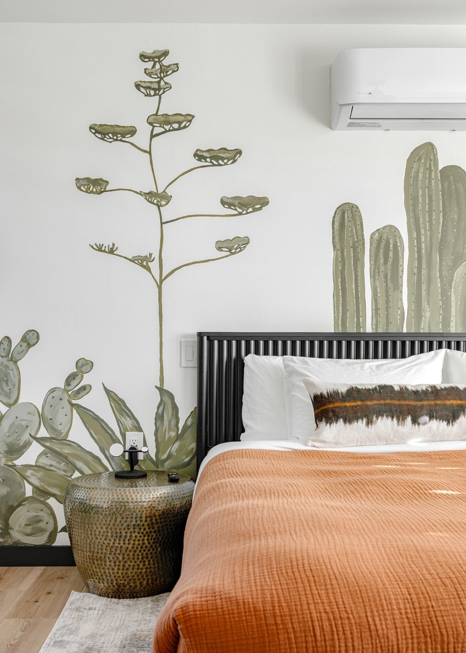 Primary bedroom with a king bed, floor-to-ceiling Sonoran Desert mural, ensuite bathroom, and walk-in closet in this Catalina Foothills vacation rental.