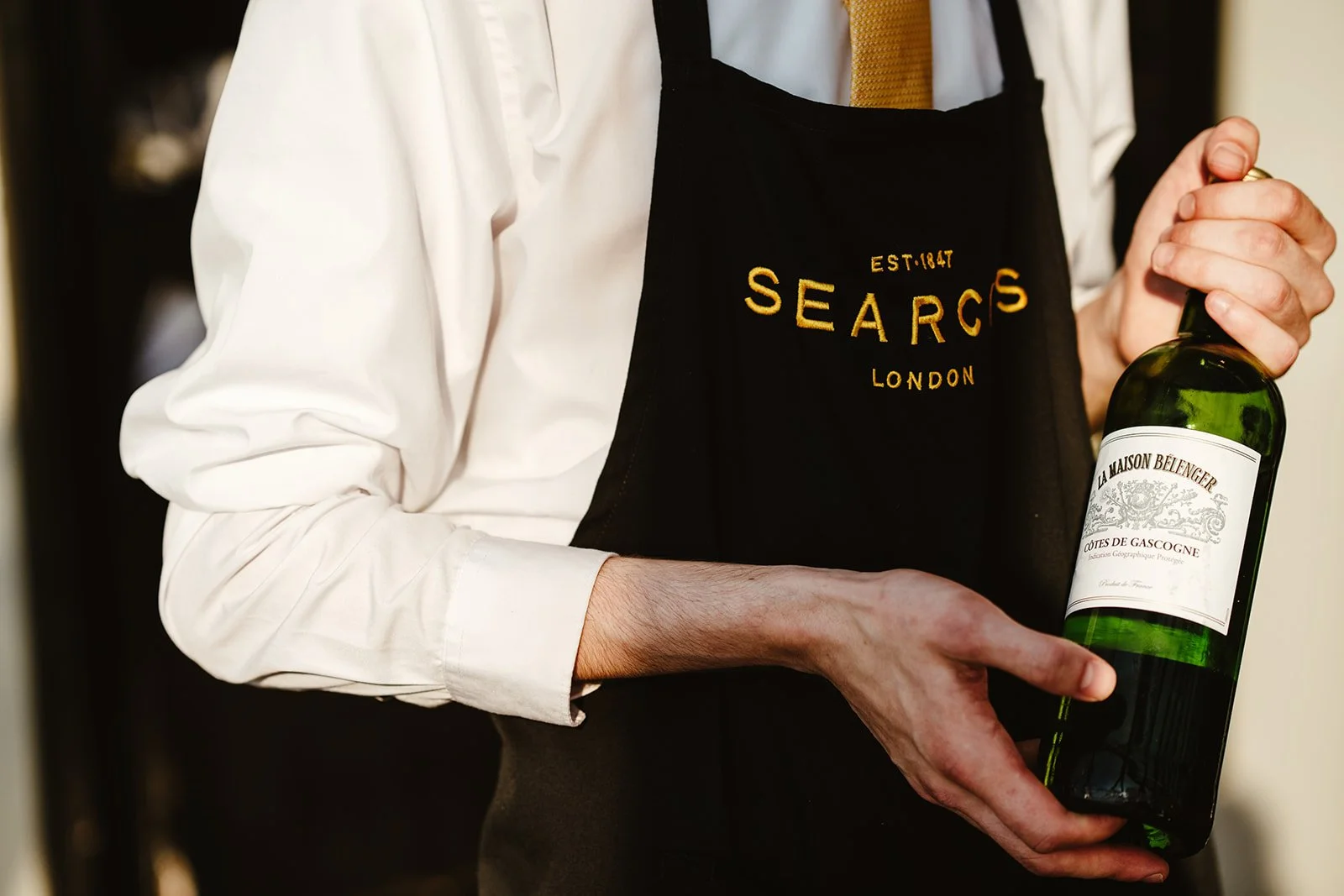 A detail of a wine bottle in the hands of a waiter at Searcys London Gherkin.