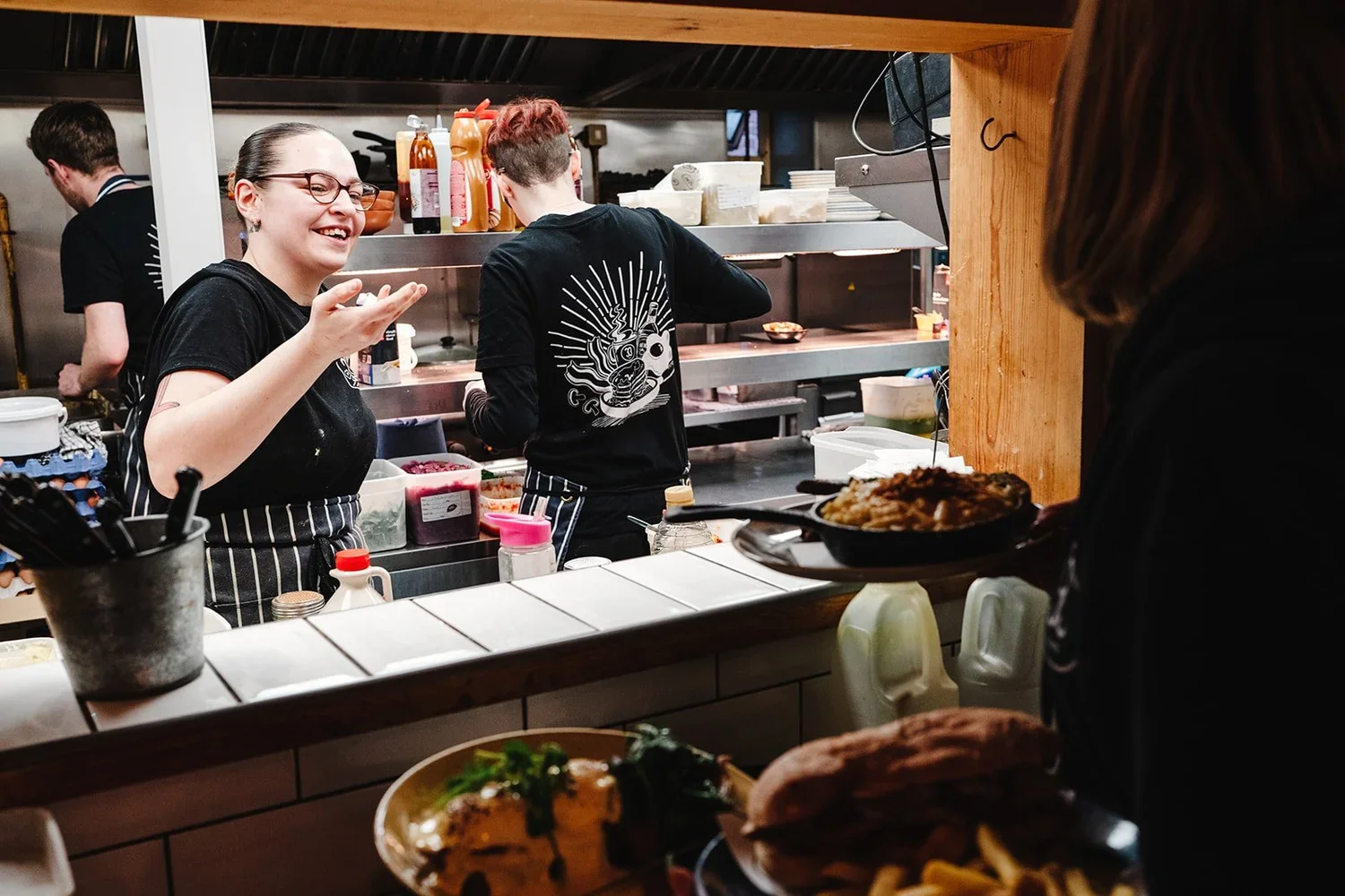 Waiting staff collect dishes from the kitchen serving hatch at No.33 cafe in Norwich.