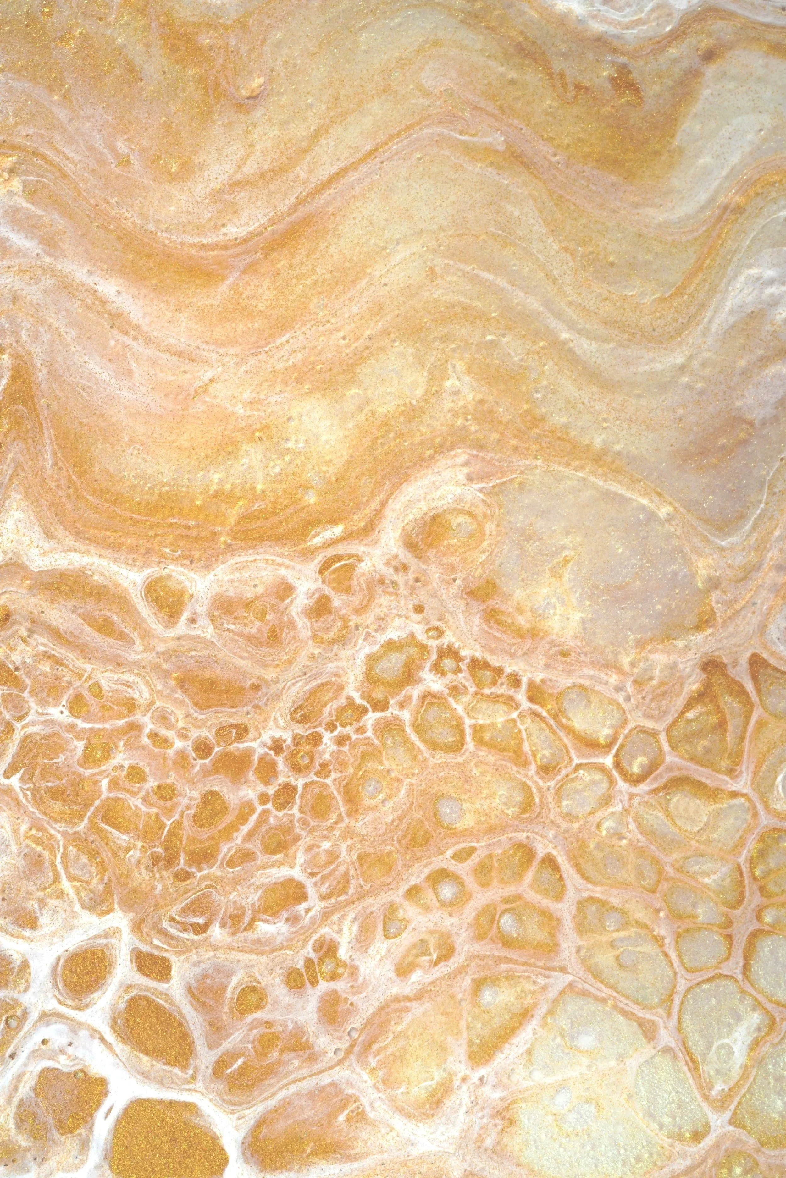 Close-up of a textured surface with swirls and bubbles in shades of tan, beige, and white, resembling marble or agate stone.